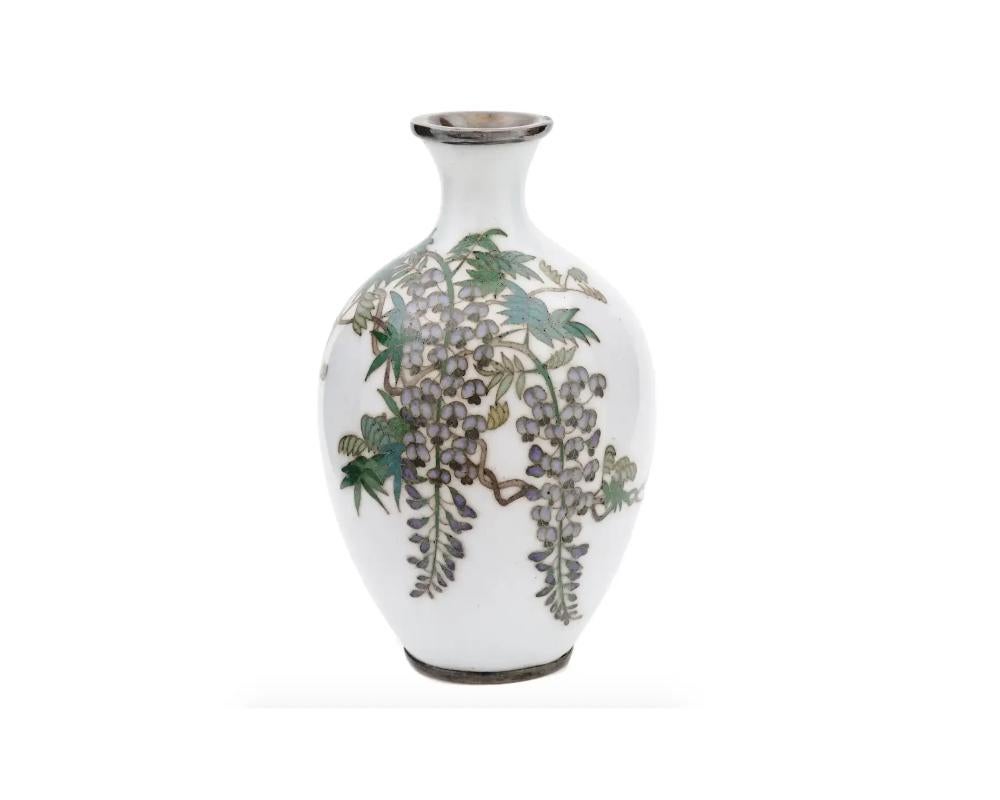 A very rare small Japanese enamel and probably Silver vase. The vase has an amphora shaped body and a fluted neck. The ware is enameled with a polychrome image of wisteria blossoming flowers made in the Cloisonne technique on a rare white ground.