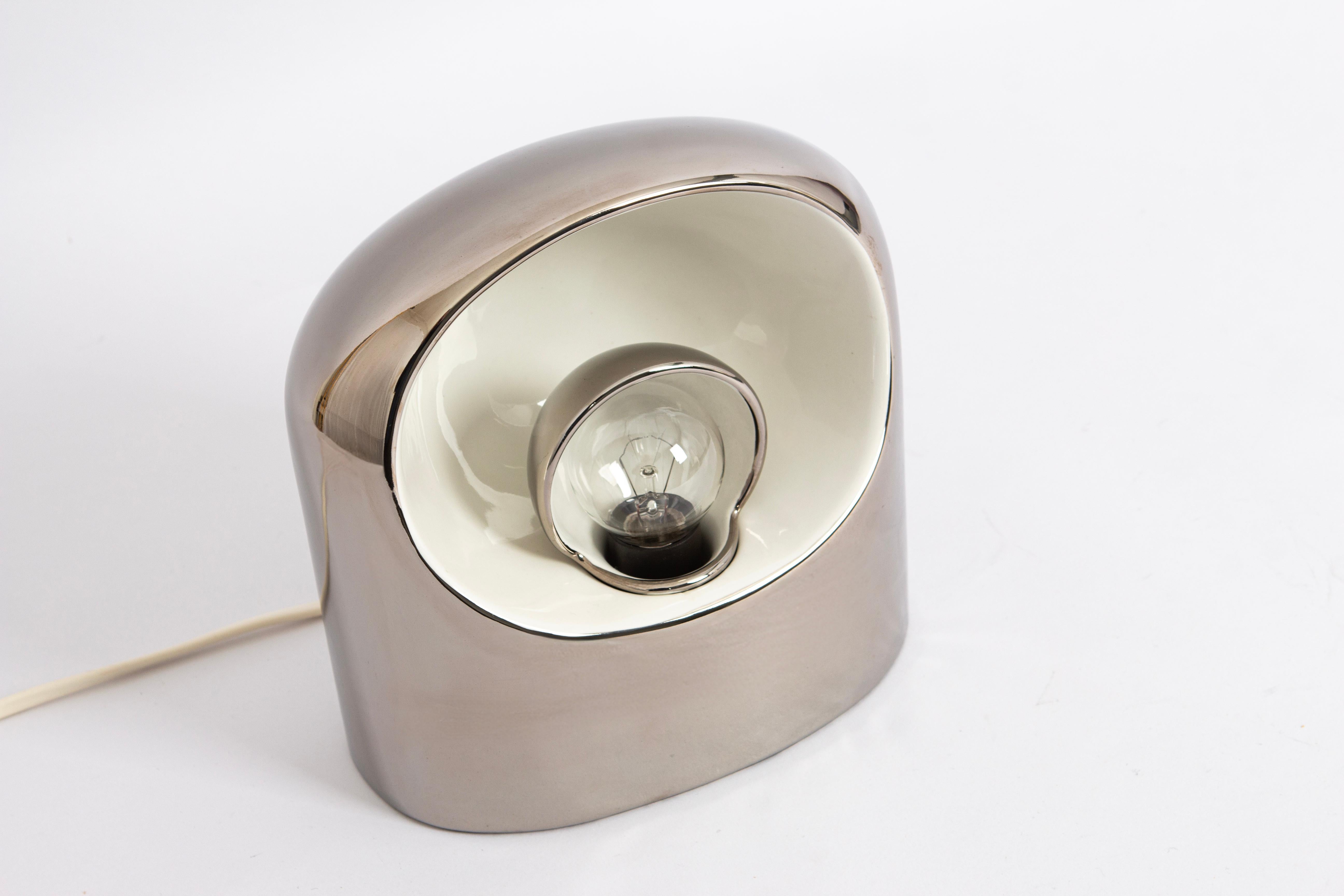 Beautiful, very rare 1970s Philips Venezia, ceramic table lamp in a silver version.
Very good vintage condition without with very few traces of wear. For direct and indirect light. The small aperture on the bulb can be turned in both