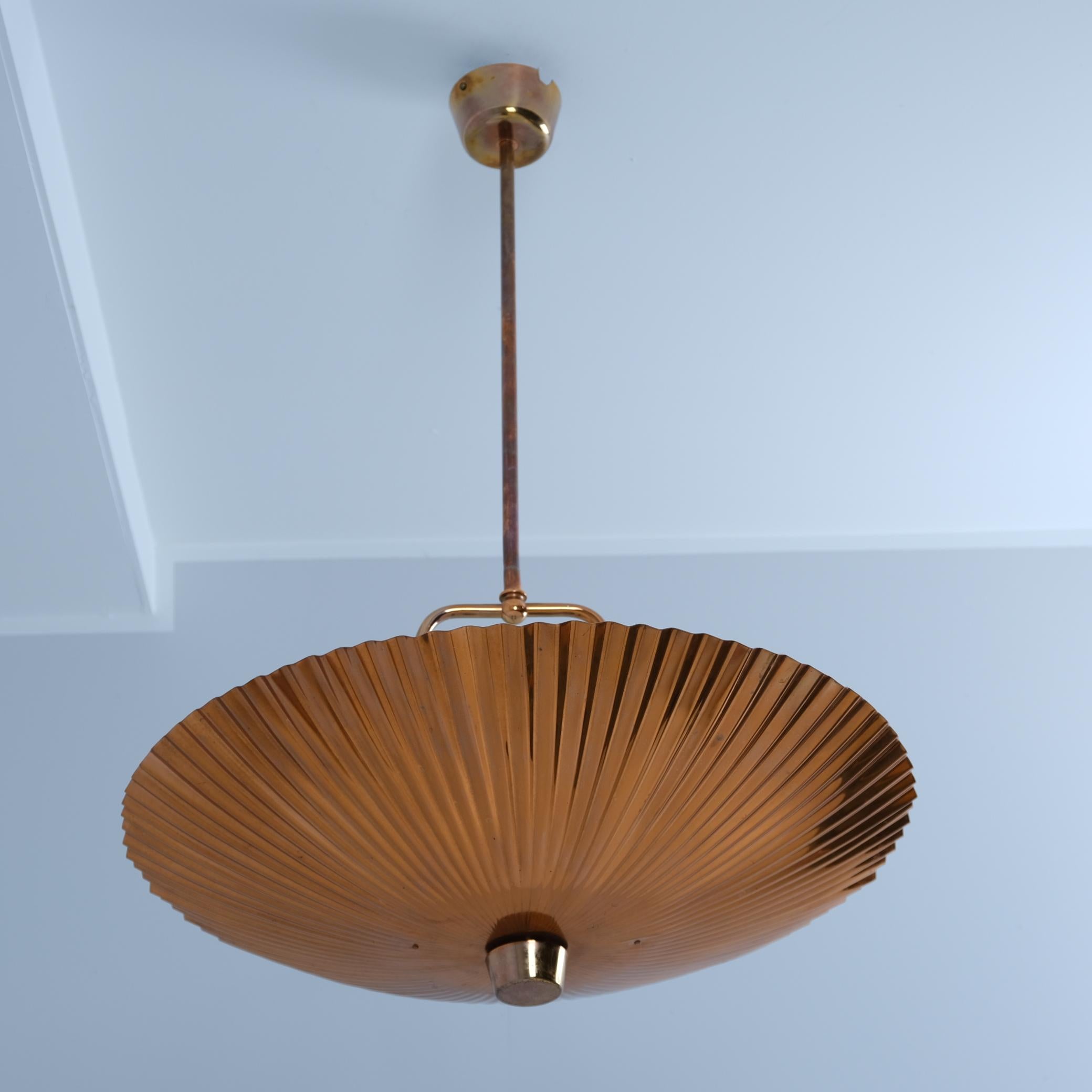Una bellissima e grande lampada da soffitto di Paavo Tynell e realizzata da Idman. Si tratta di una rara versione di questa lampada realizzata in rame. La superficie a conchiglia del paralume è stata utilizzata anche in una lampada da tavolo di