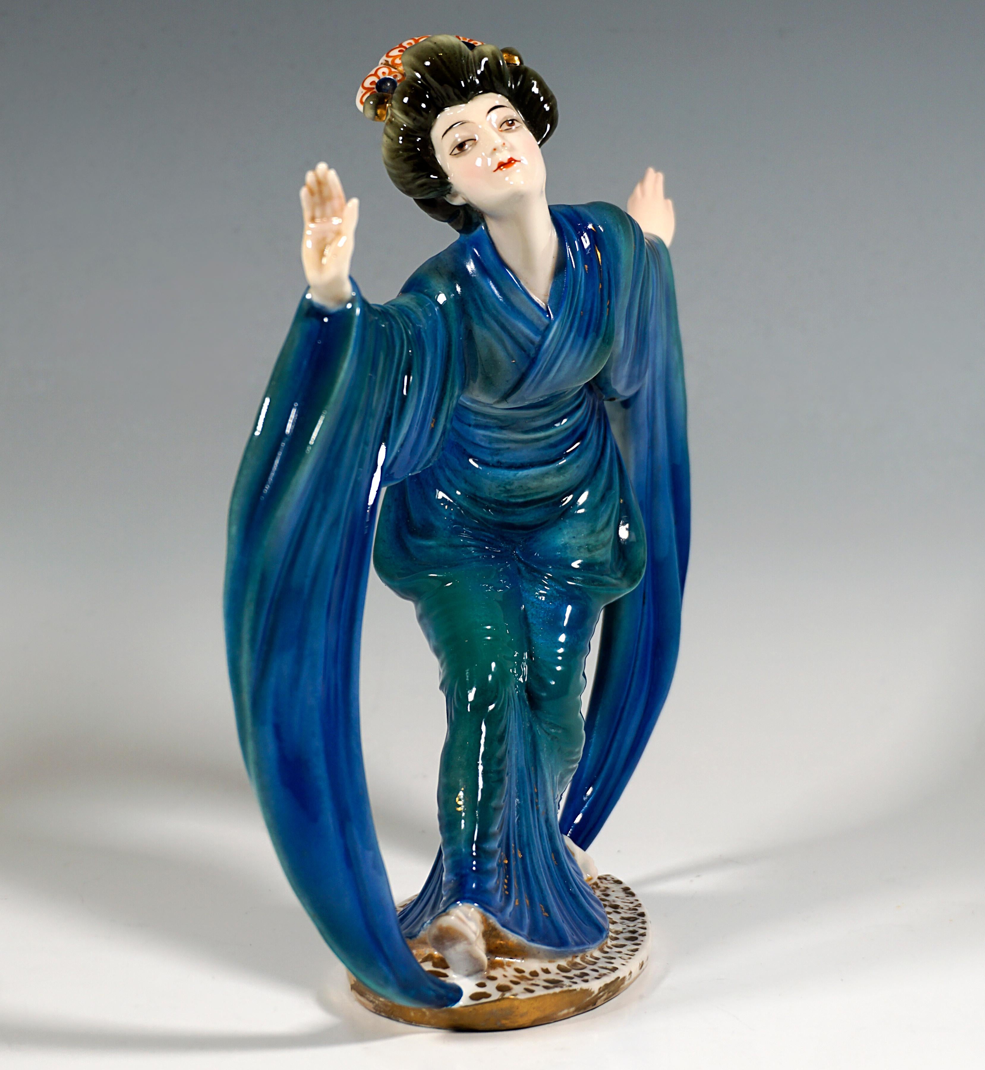 Very rare and exceptional Marcell Goldscheider ceramic figurine:
A geisha, as a highly qualified Japanese actress and artist, in an elaborate masquerade with typical headdress in traditional garb in blue-green, in a slightly stooped posture and with