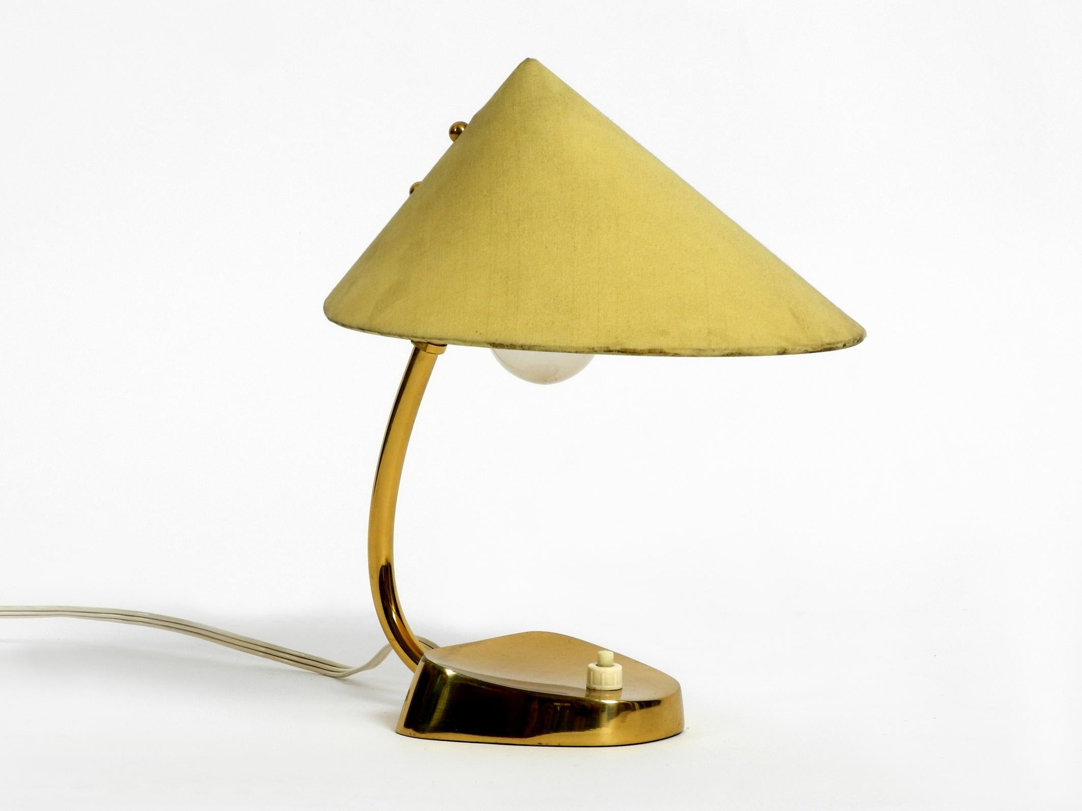 Very elegant original midcentury brass table lamp with fabric shade. 
Manufacturer J. T. Kalmar. Made in Austria in the 1950s.
Heavy brass base and neck, light green fabric shade. 
Beautiful Minimalist design for very pleasant light. 
No damage