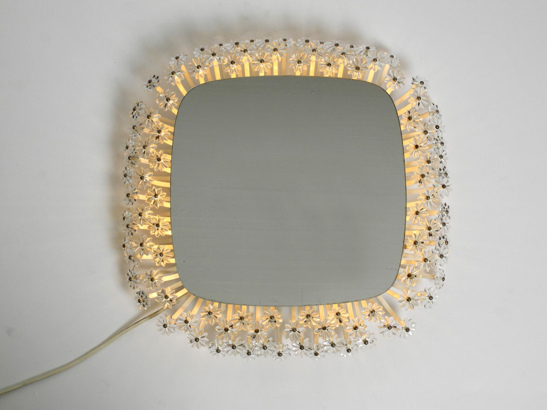 Beautiful rare backlit Mid-Century Modern flower mirror by Rupert Nikoll. 
Great complex design with lots of small plastic flowers.
We are illuminated on the back with an E27 bulb with a maximum of 60W.
Very good vintage condition. Mirror not