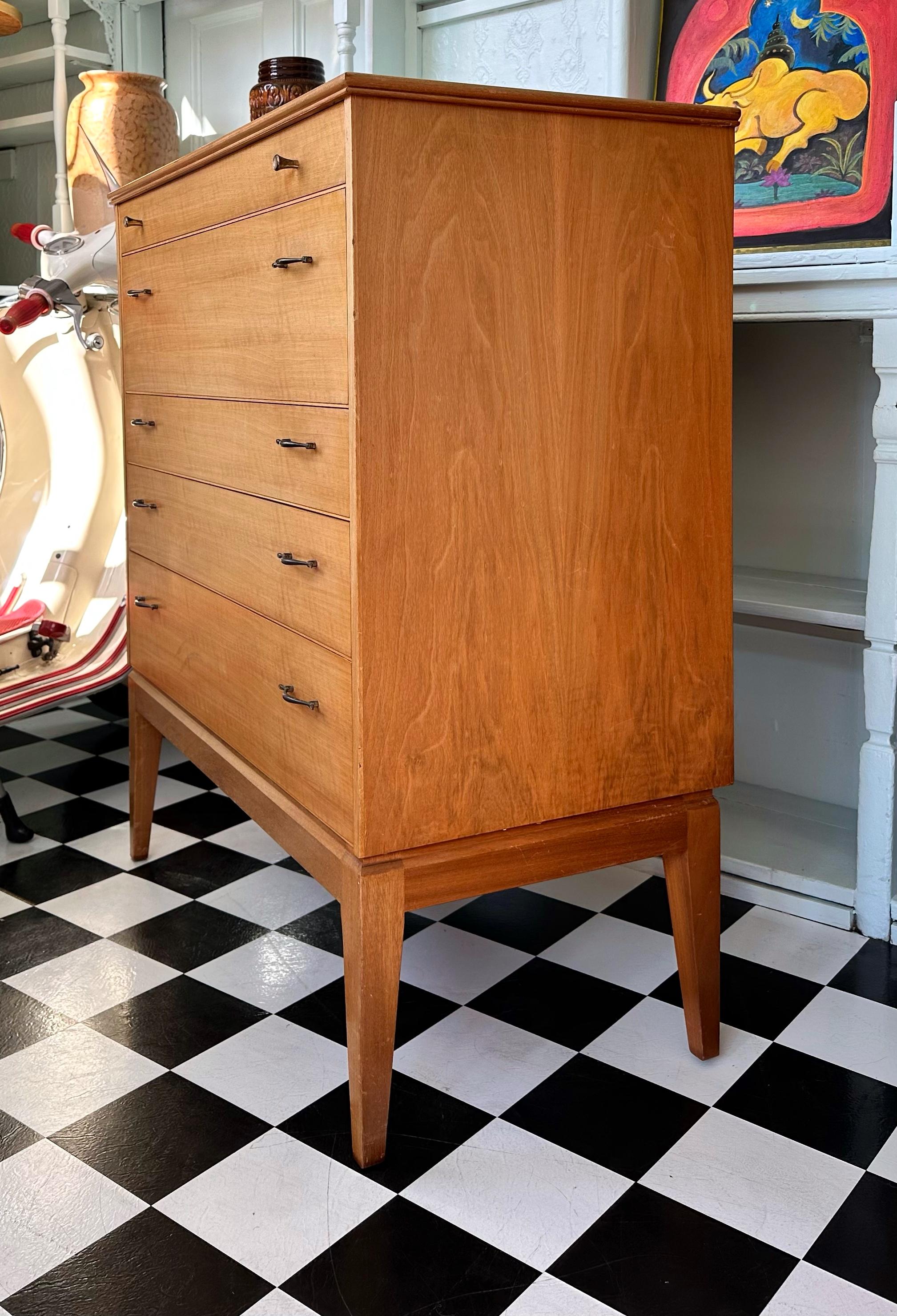 Very rare Mid Century modern teak and walnut tall chest of drawers. Designed in 1960s by the renowned and highly collectible cabinet maker Alfred Cox of Great Britain. Features five spacious drawers with stylish metal handles and stunning splayed