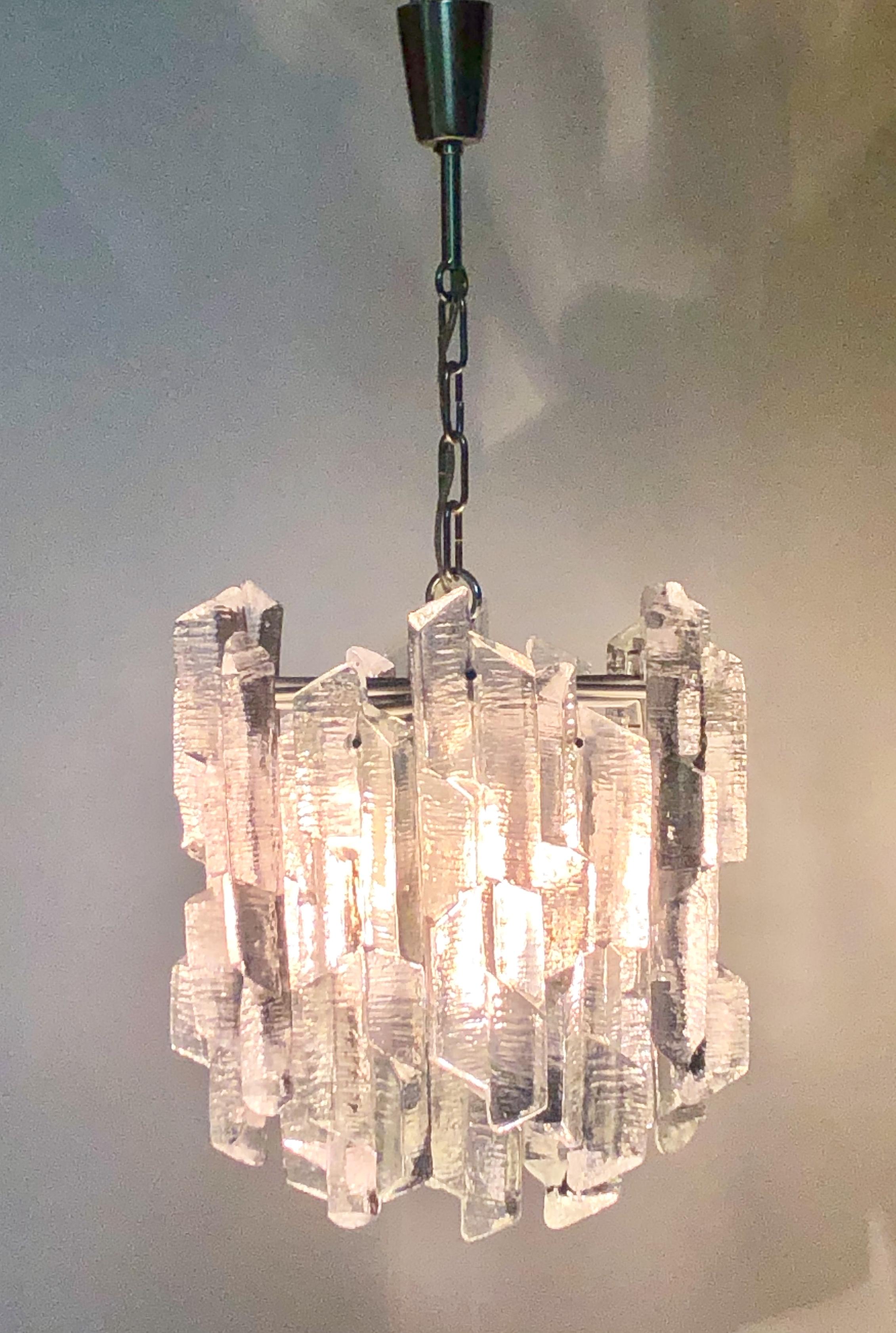 A  rare ice glass chandelier by J.T.Kalmar, Austria, circa 1960s.
The chandelier is made of nickeled metal frame with 18 thick clear Murano structured glass blocks.
Socket: 6 x e14 and 1 x e27 (for standard screw bulbs).
Weight: ca. 25 kg.

New
