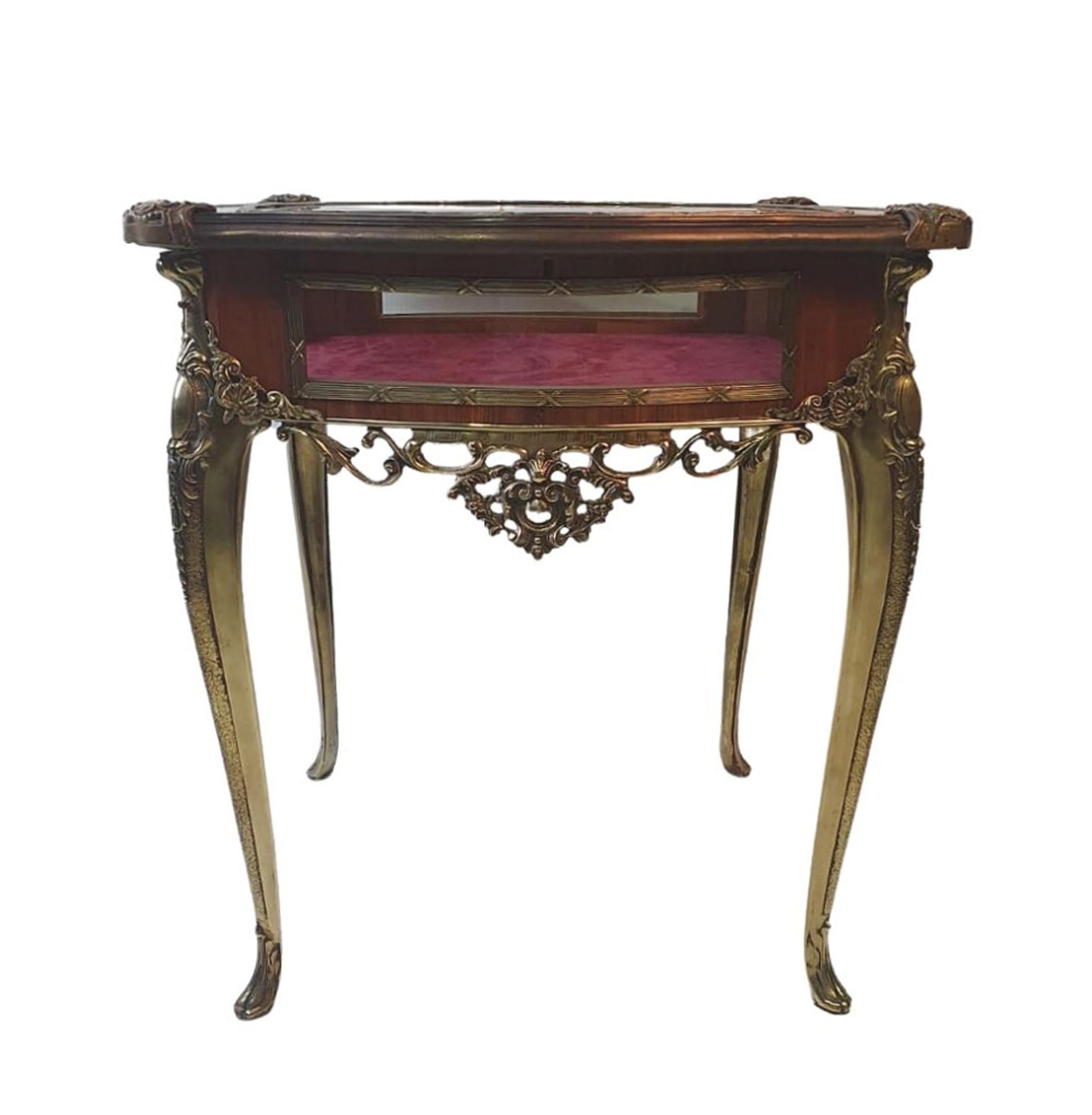 Rare 19th Century museum quality brass and kingwood bijouterie table, the shaped and moulded top with brass mounted sides, cross banded in kingwood and with centred brass framed glass window opening to a red velvet interior. The frieze with four