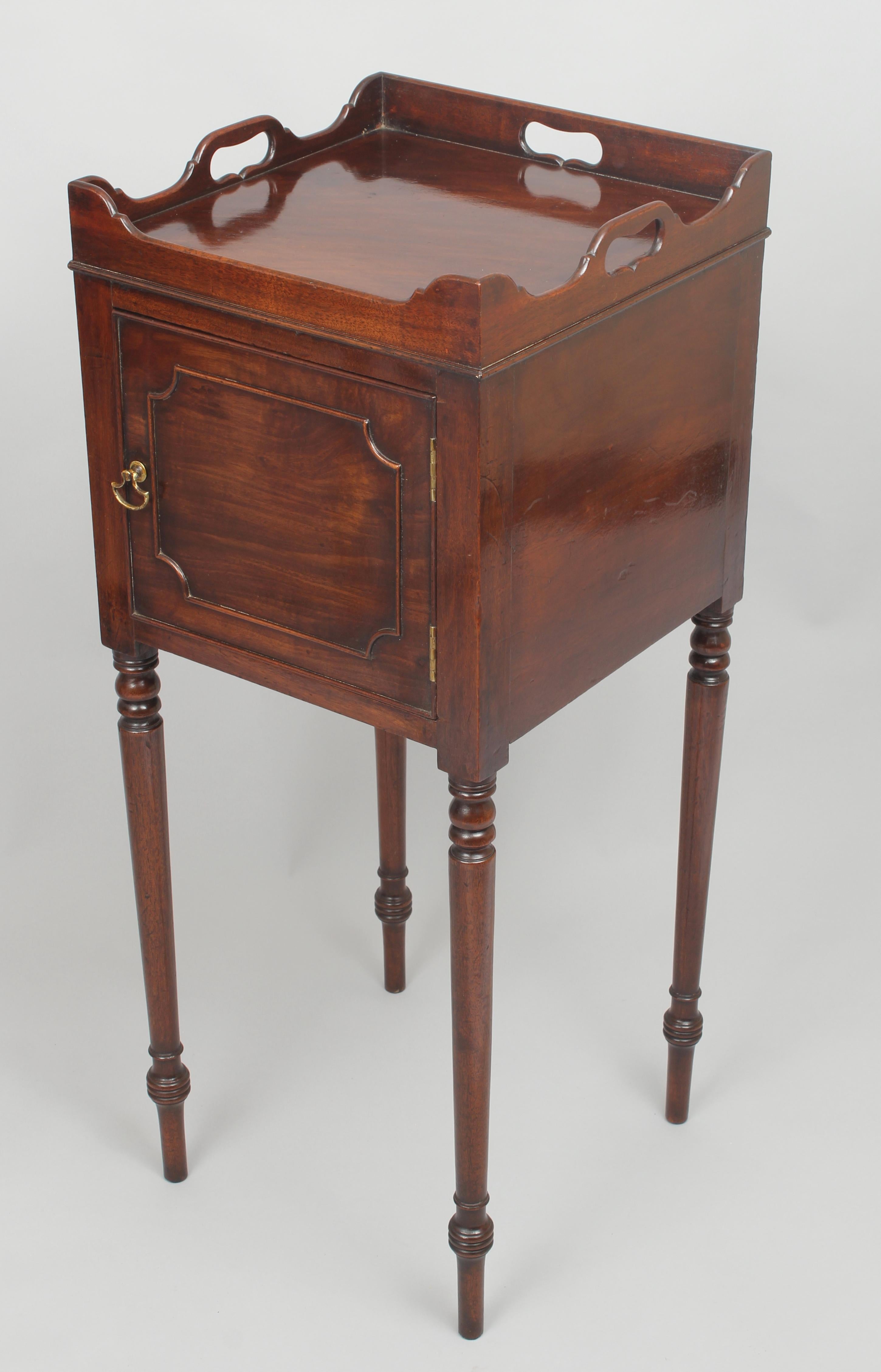 A very rare pair of George III period mahogany bedside pot-cupboards of rich-coloured timber; each with slatted bases, shaped three-part galleries and left and right hung doors with astragal-moulded panels, on slender turned legs.