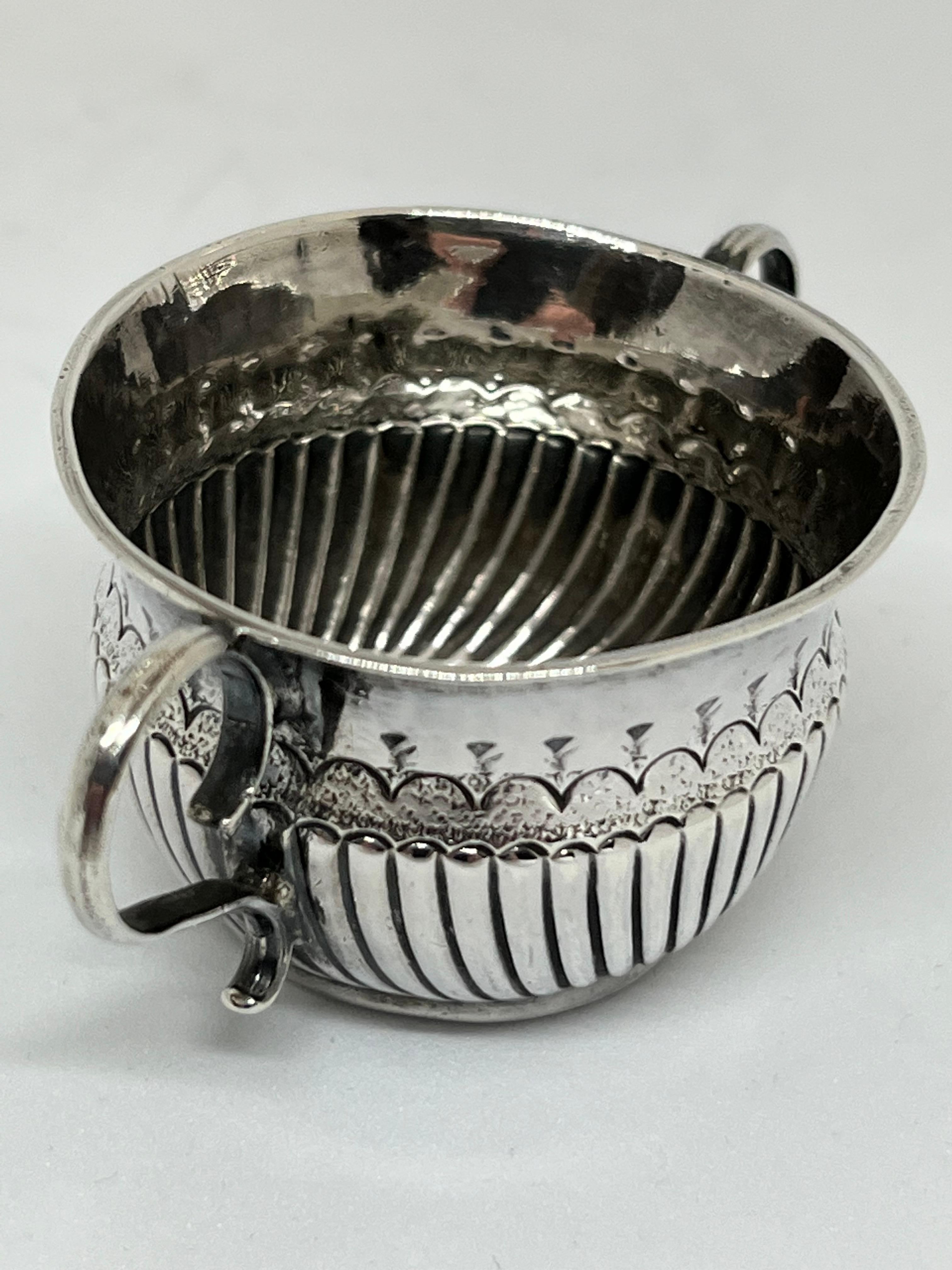 Queen Anne Silver Dram Cup. Maker: William Fleming. London, 1710.

A Queen Anne Britannia Standard (0.958%) silver dram cup, these are also often referred to as a miniature, or toy, two handled porringer, the body with fluting to the lower half,