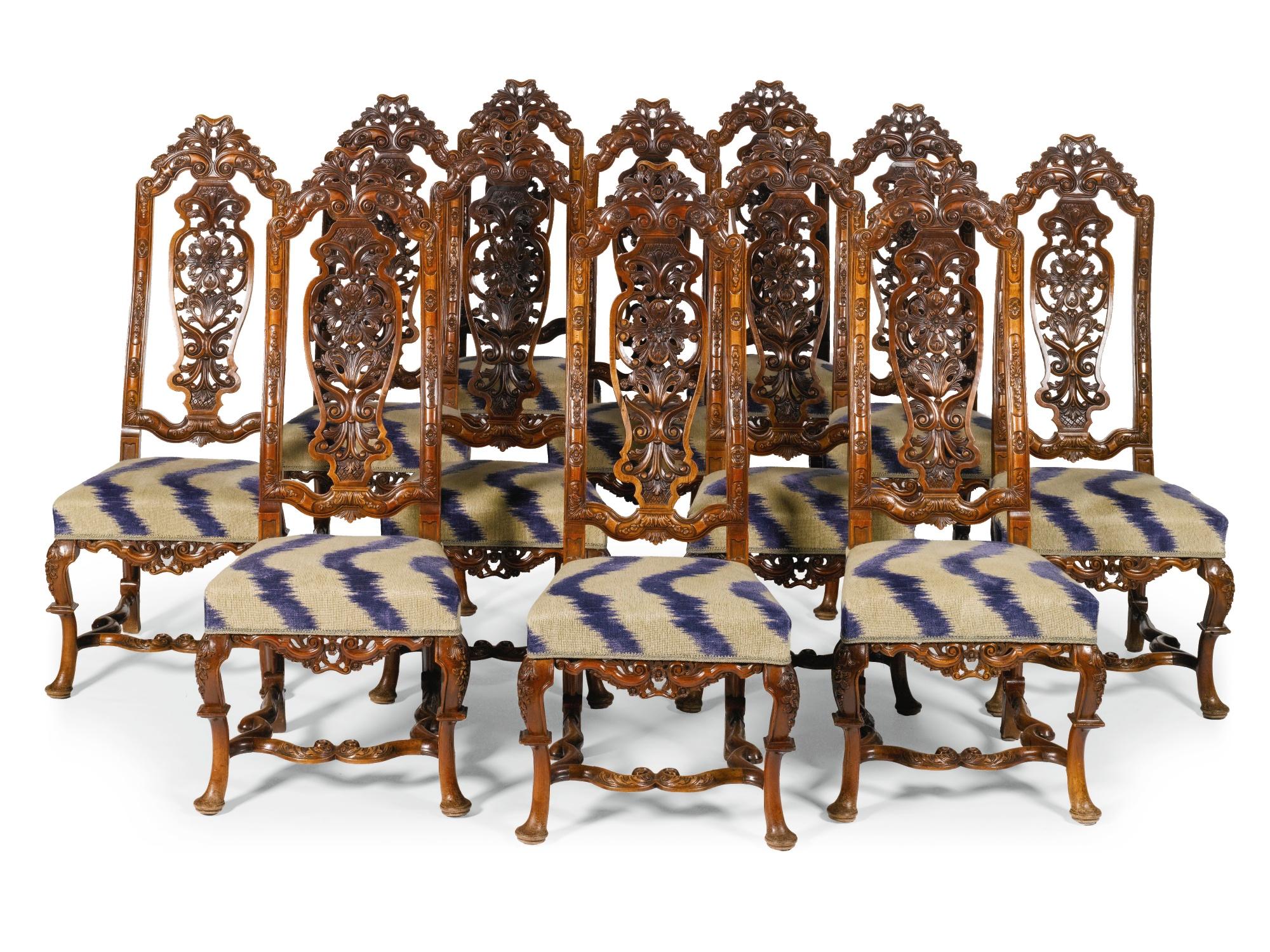 The high backs have carved and shaped top rails with double scrolls surmounted by open and pierced sprays of acanthus leaves and rosettes. The side rails to the backs are carved with panels set with rosettes flanked by husk drapery. The seats are