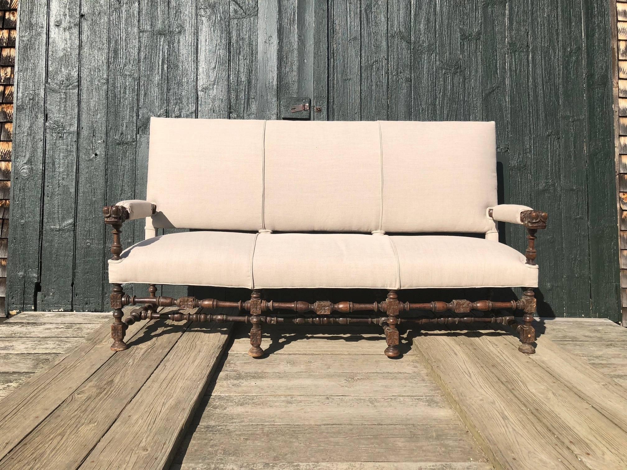 Unusual very early French sofa with rare Baroque stretcher form. Newly upholstered, this magnificent sofa offers a significant carved antique frame.