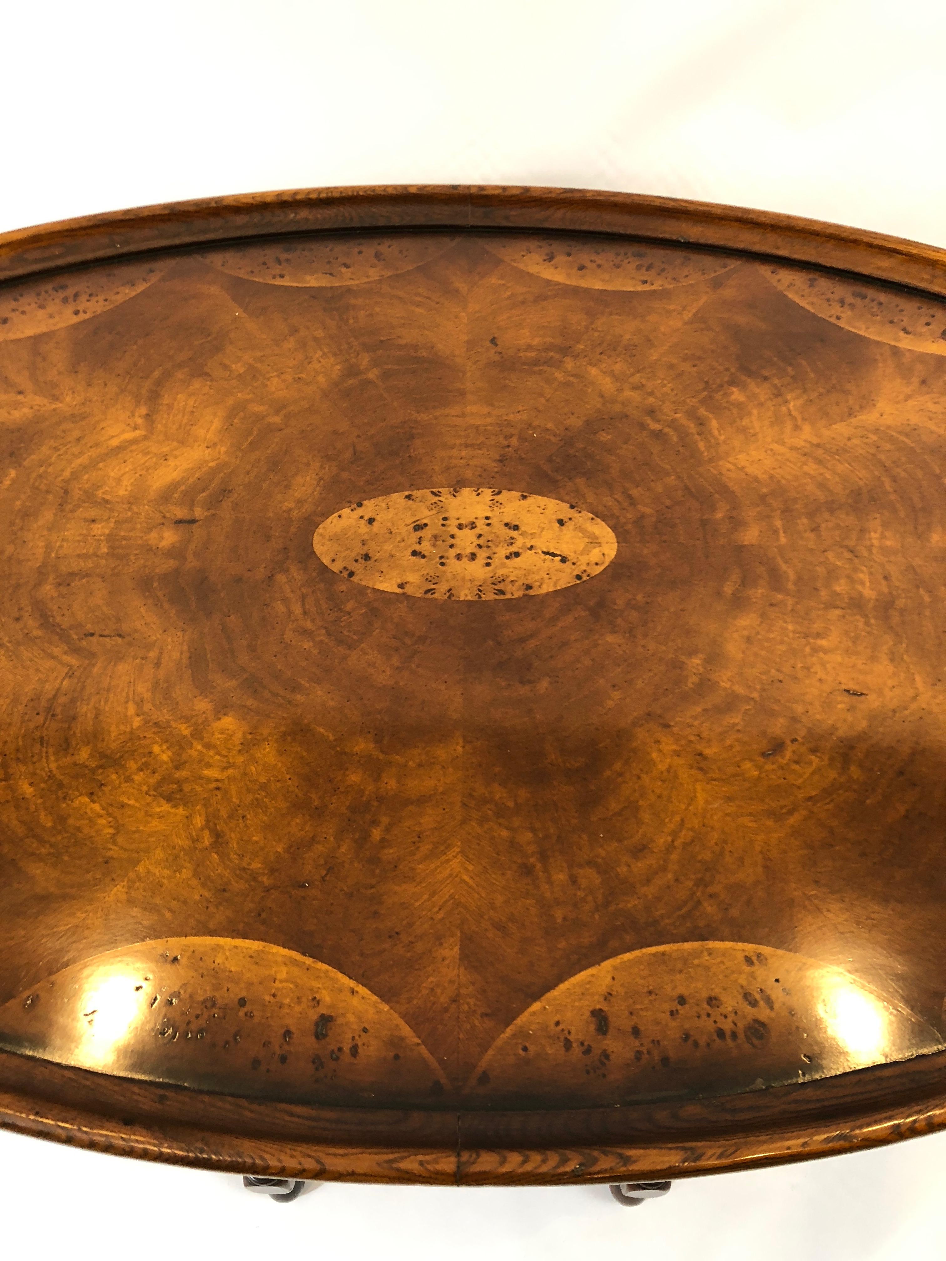 Richly impressive oval burl wood coffee table having an inlaid top with scallop design around the periphery, central medallion, oak surround, intricate network of turned legs, and wonderful pullout / pull-out slides at each end. Beautiful