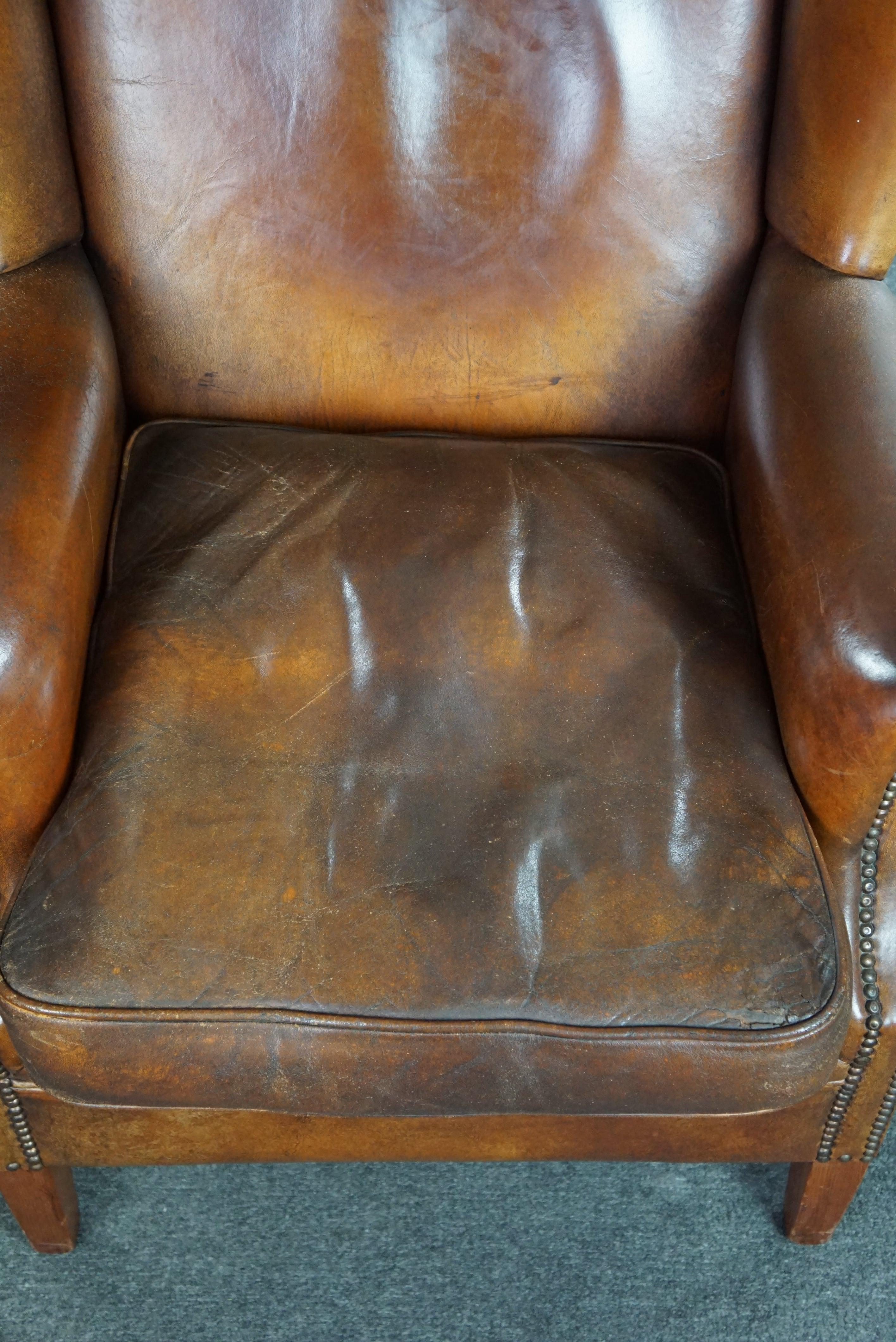 Very rugged wingback armchair made of cognac-colored sheep leather For Sale 1