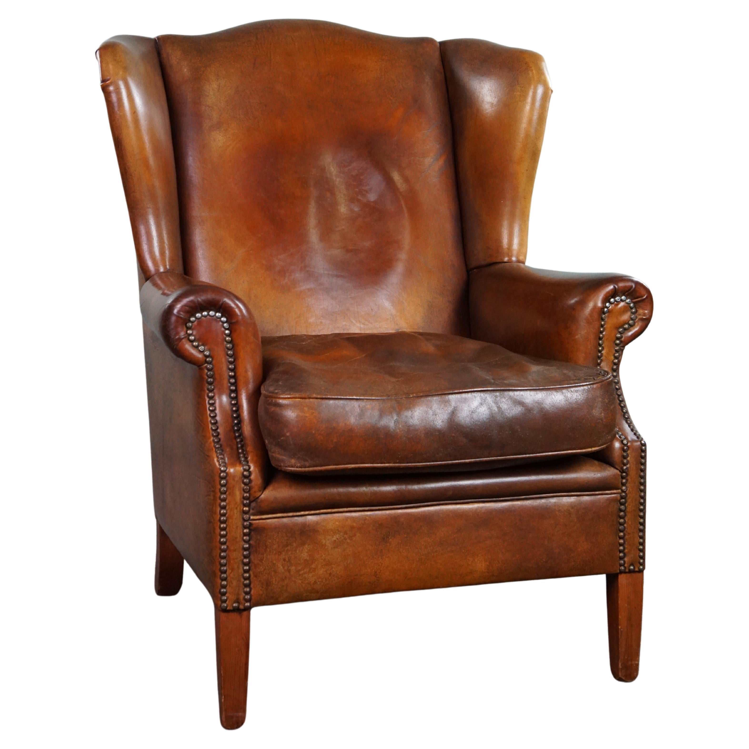 Very rugged wingback armchair made of cognac-colored sheep leather For Sale