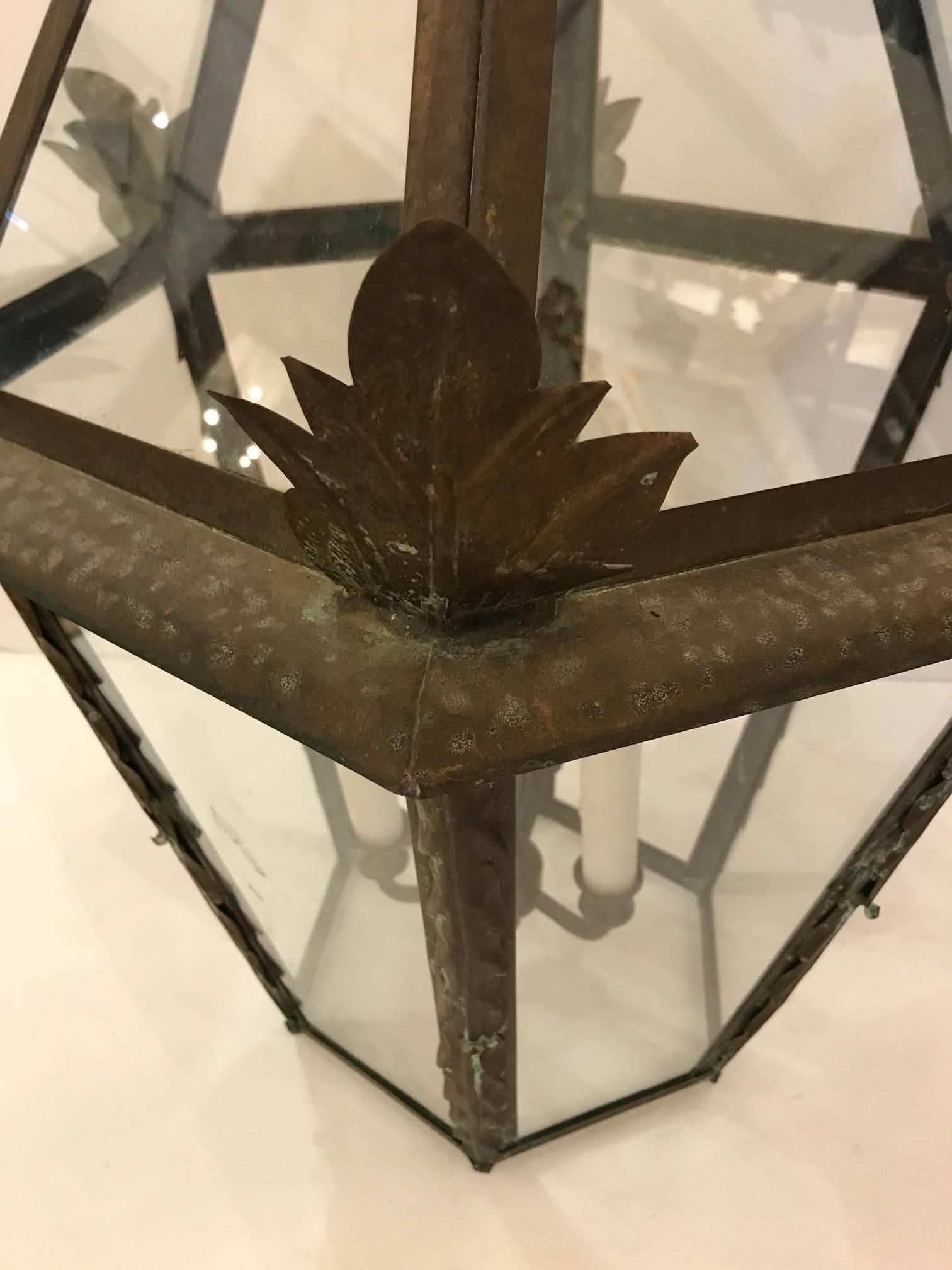 Wonderful large French copper lantern with Verdigris finish having decorative leaves around the top periphery and three lights, 60 watt each with white wax candle sleeves.
18 inches of chain included and original ceiling cap.
