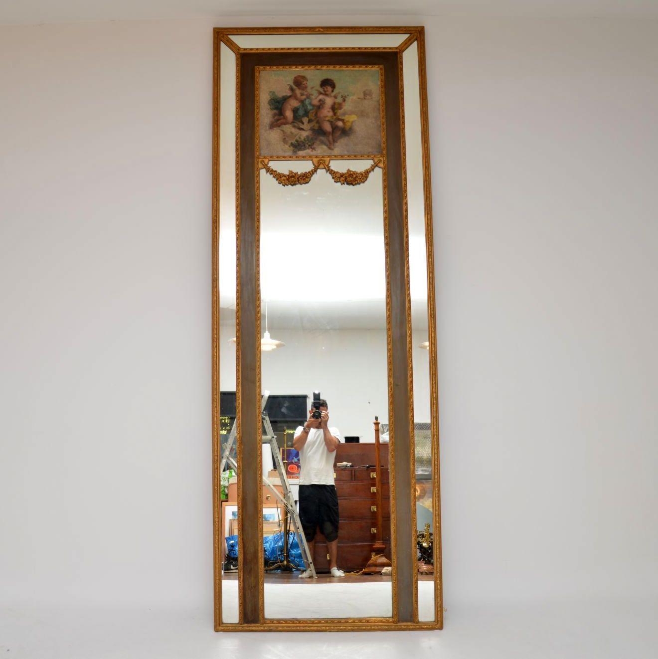 Grand miroir décoratif antique en bois doré avec une peinture à l'huile signée sur la section supérieure et d'autres caractéristiques merveilleuses.

Il est très difficile de montrer une bonne image de ce miroir et de rendre compte de ses grandes