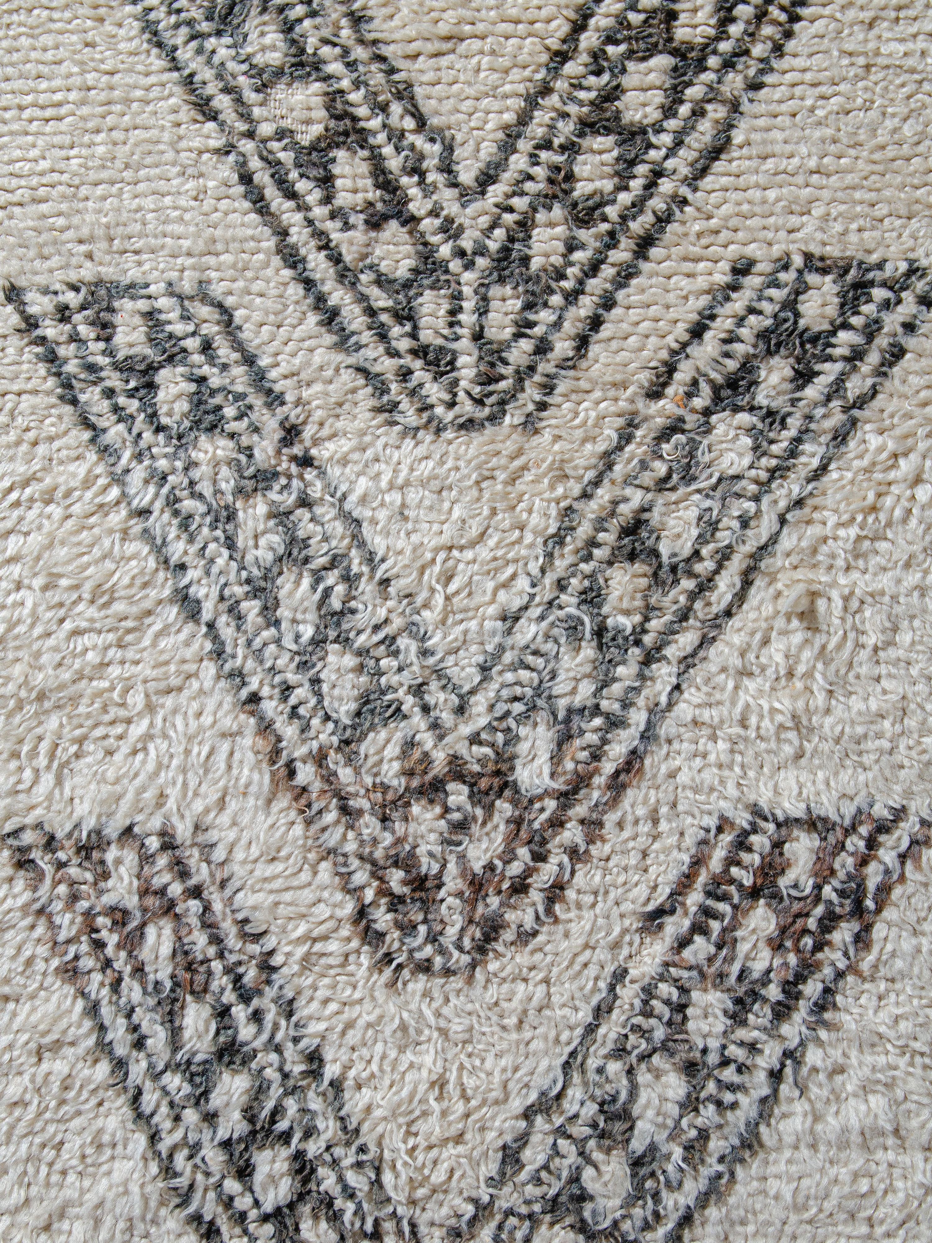 Insólita alfombra marroquí Beni Ouarain de época que presenta un par de bandas verticales de formaciones en V segmentadas por elaborados motivos de cadenas en dos estilos distintos. El dibujo está incrustado en un extremo, lo que proporciona una