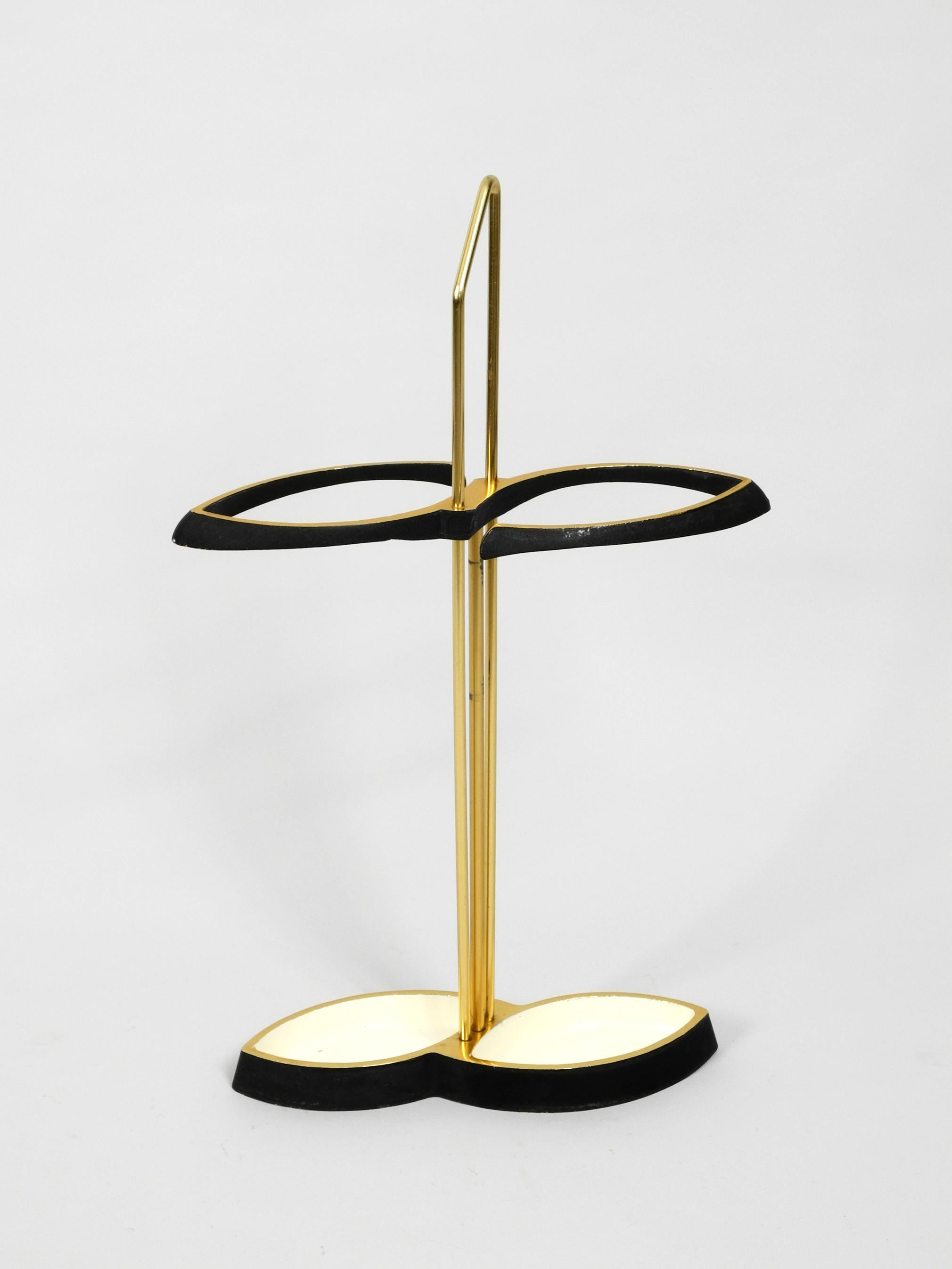 Very elegant, fancy Mid-Century Modern umbrella stand, made entirely of brass.
Minimalistic, high-quality design with a brass frame, partly in glossy white
and painted in matt black.
The foot has been made heavier with two iron components, due to