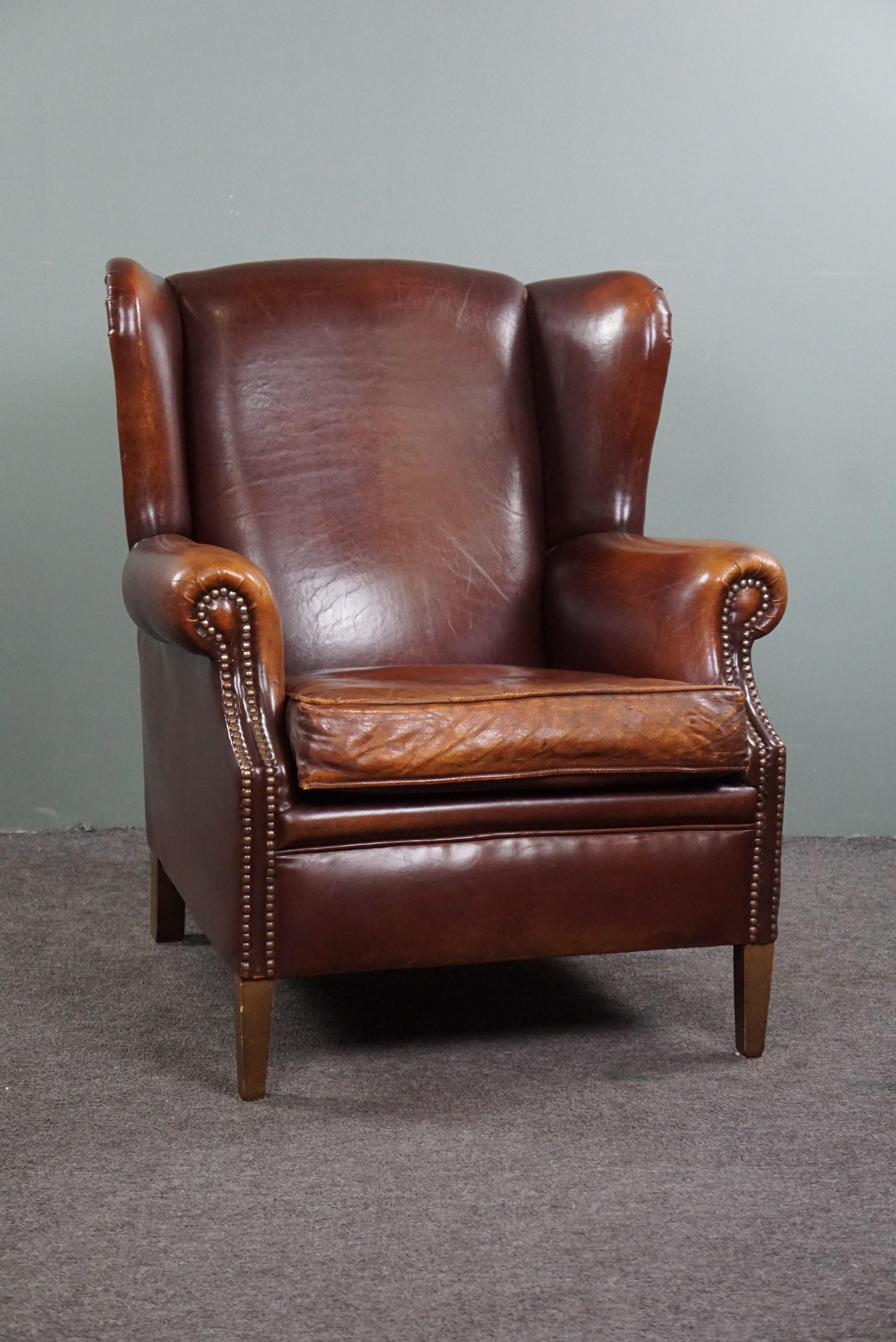 Offered this beautiful sheep leather wing chair finished with beautiful decorative nails.

This pearl has a beautiful warm color and a beautiful patina.
Anyone who takes this unique eye-catcher into their home is assured of a wonderfully seated and