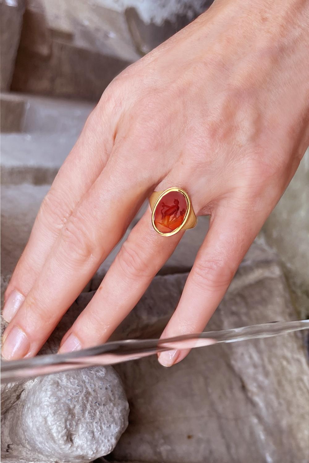 In this 18 Kt gold ring, an authentic Roman carnelian (II-III century AD) has been set, depicting the goddess Vesta, with the bronze tripod (where the sacred fire is kept) in her left hand and the snake in her right hand.
Vesta, in Roman religion,