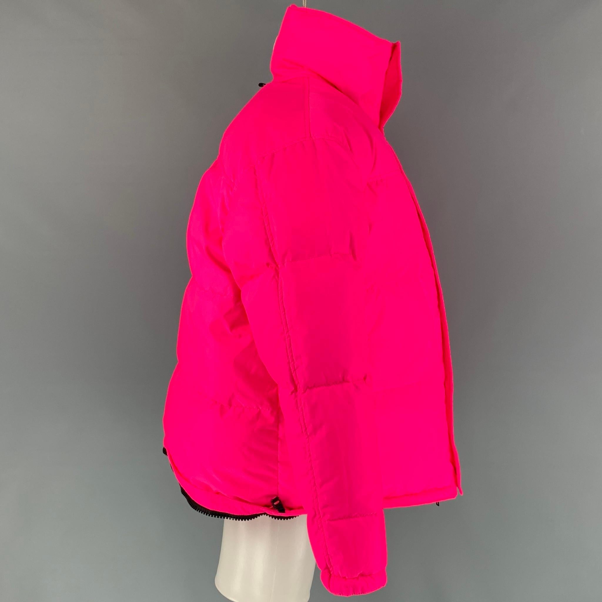 VETEMENTS FW 19 jacket comes in a fluo pink quilted polyester featuring a oversized fit, hidden hood detail, drawstring hem, high collar, slit pockets, and a snap button closure. Jacket could styled as a cropped jacket using the hidden zip fasteners