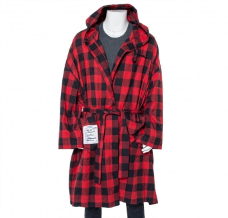 Vetements SS 2018 belted robe. Made from cotton, the flannel robe has plaid patterns in red and black. It features long sleeves, dropped shoulders, a hood, pockets, and a detachable tie at the waist.