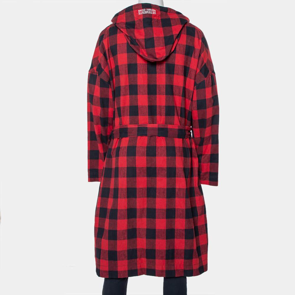 Vetements SS 2018 Robe mit Gürtel. Der Flanellmantel ist aus Baumwolle gefertigt und hat ein Karomuster in Rot und Schwarz. Er hat lange Ärmel, überschnittene Schultern, eine Kapuze, Taschen und eine abnehmbare Krawatte in der Taille.

Enthält: