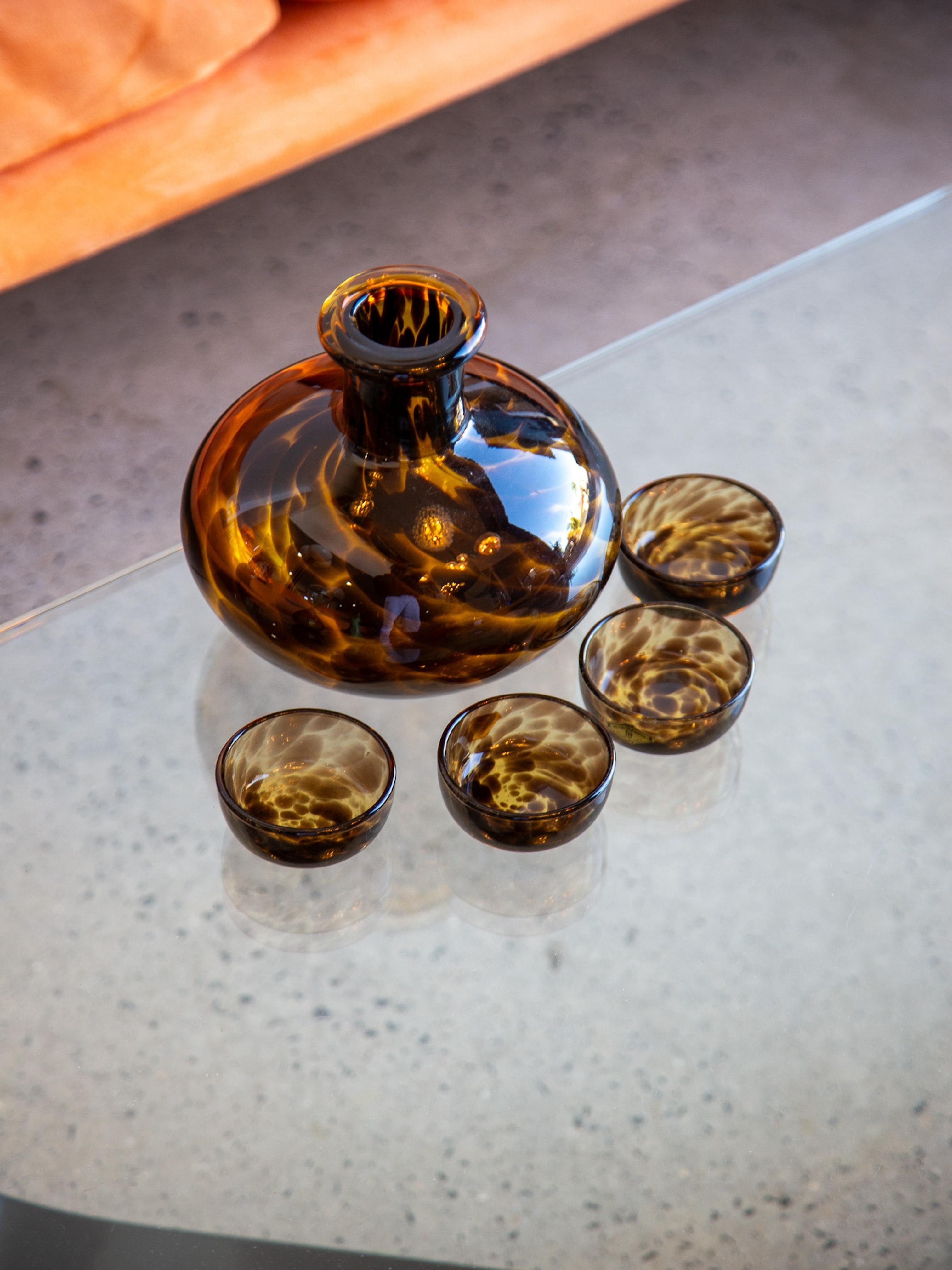 Questo set di decanter in vetro del Mid Century Modern è stato prodotto da Vetri Empoli in Toscana durante gli anni '60. L'insieme comprende un decanter generosamente arrotondato con un ampio collo, abbinato a quattro bicchieri coordinati, tutti