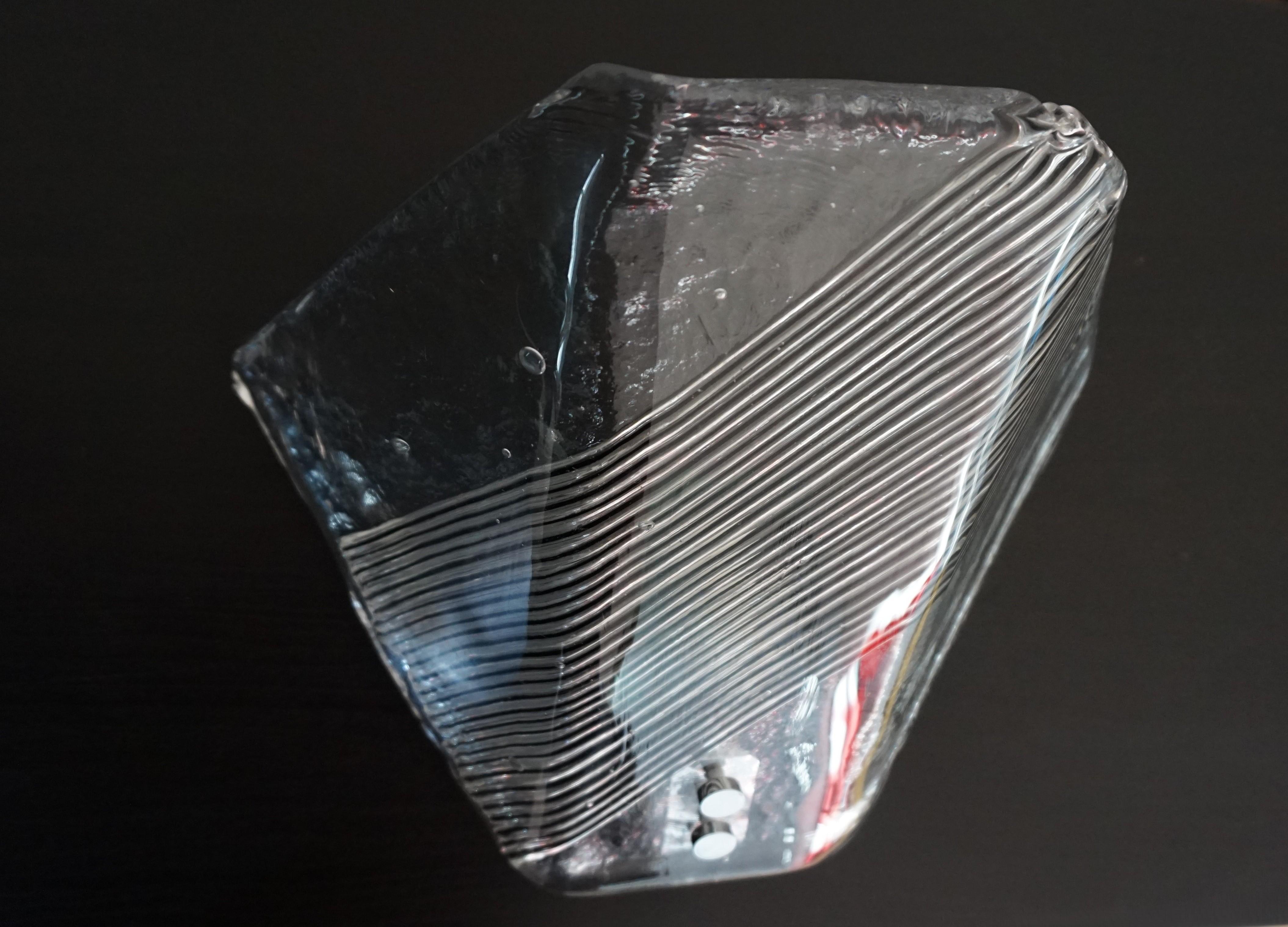 Questa lampada da parete è in ottime condizioni. Lo spessore di quasi 1 cm del vetro di Murano soffiato a mano con alcune sacche d'aria crea un leggero effetto ghiaccio. Il vetro trasparente è interrotto da scanalature nel vetro interno che