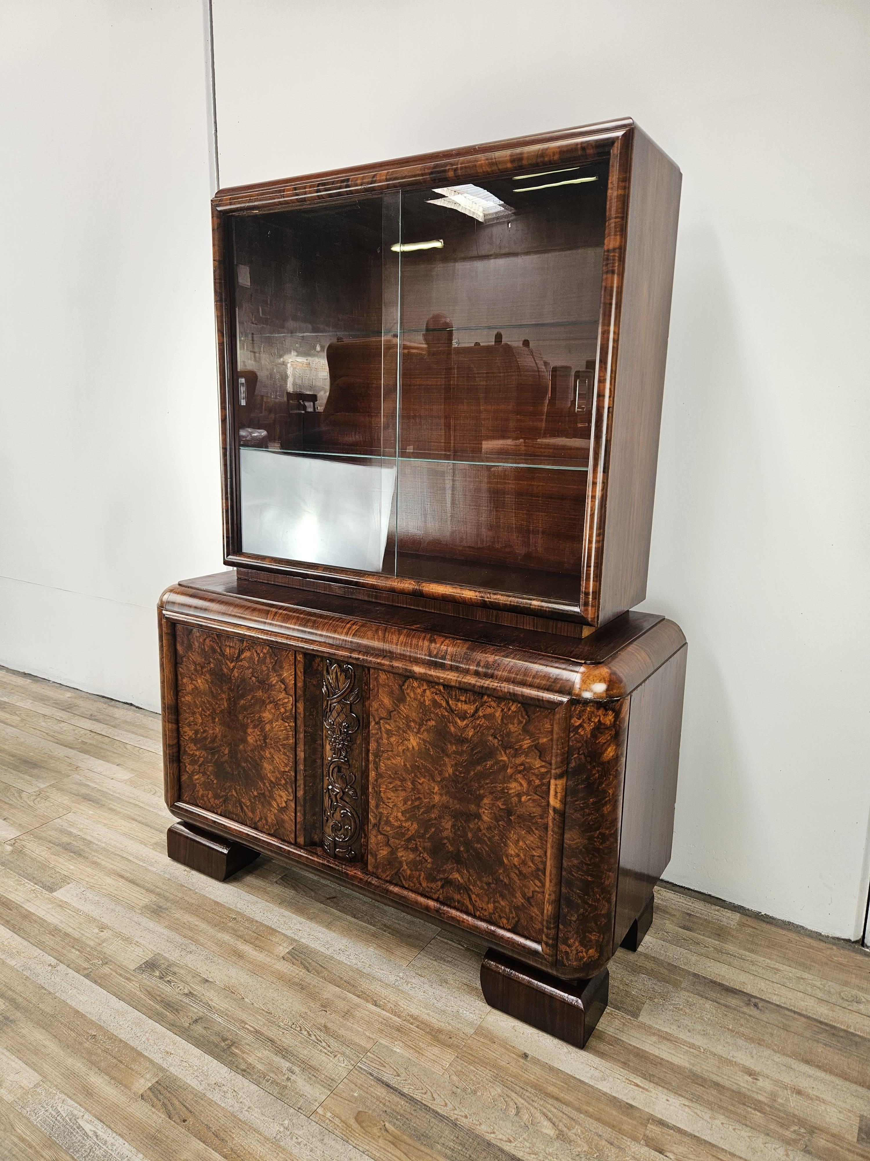 Antique 1930s Art Deco cabinet of German origin with double-body frame made of walnut burl and solid walnut.

At the top there is a display case with sliding glass and double transparent inner shelf, while at the base there is a compartment with
