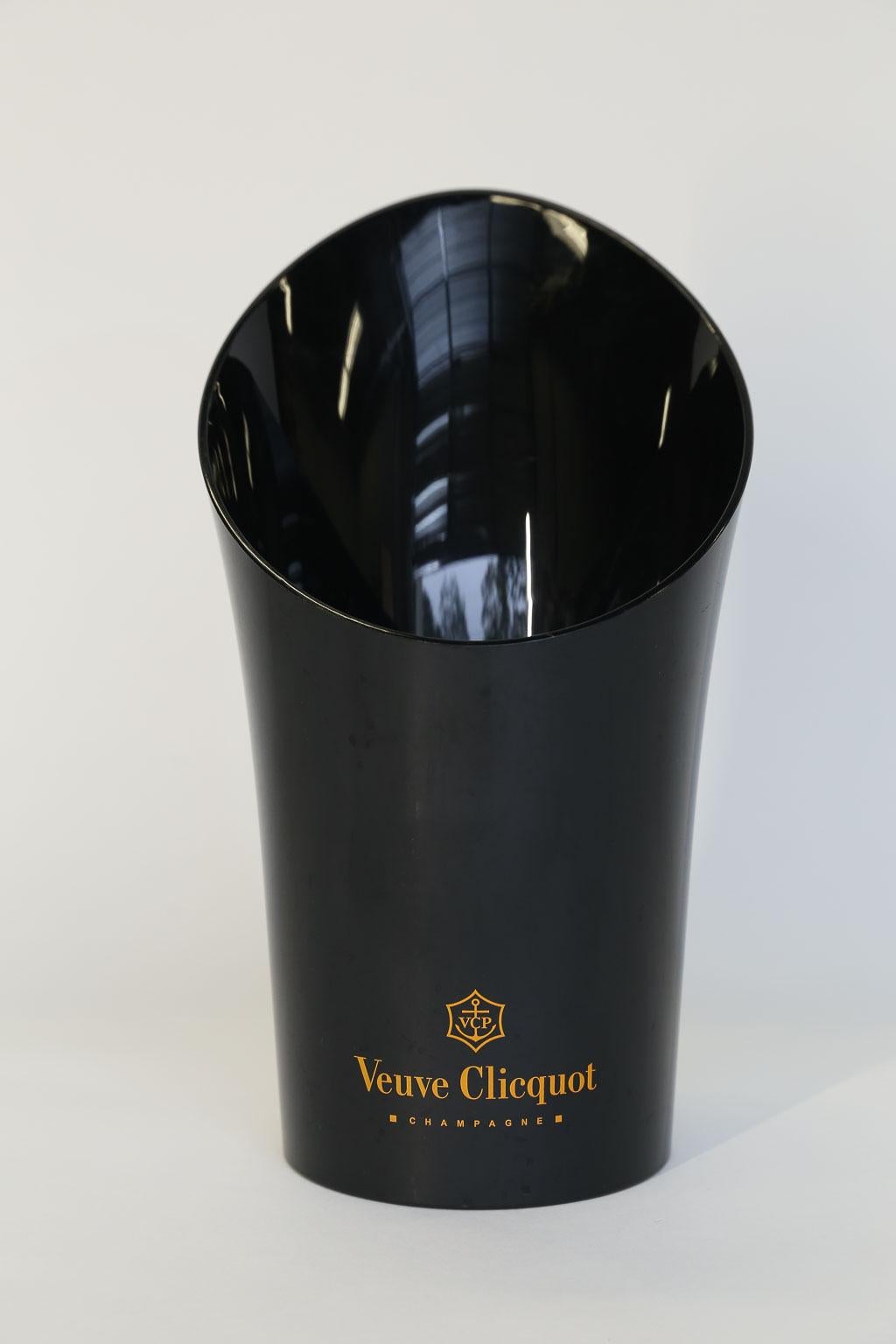 Made by the House of Veuve Clicquot for cooling champagne at outdoor celebrations, this black acrylic wine cooler is decorated with Veuve Clicquot's insignia on the front and an engraved logo on the back. The sleek black color and shape make this a