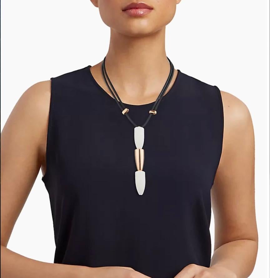 This Vhernier necklace from the Calla Collection features a pendant with three elements crafted in 18K gold and restructured kogolong, with a rubber cord. The design is sleek and modern, with elongated, tapered forms arranged in a vertical