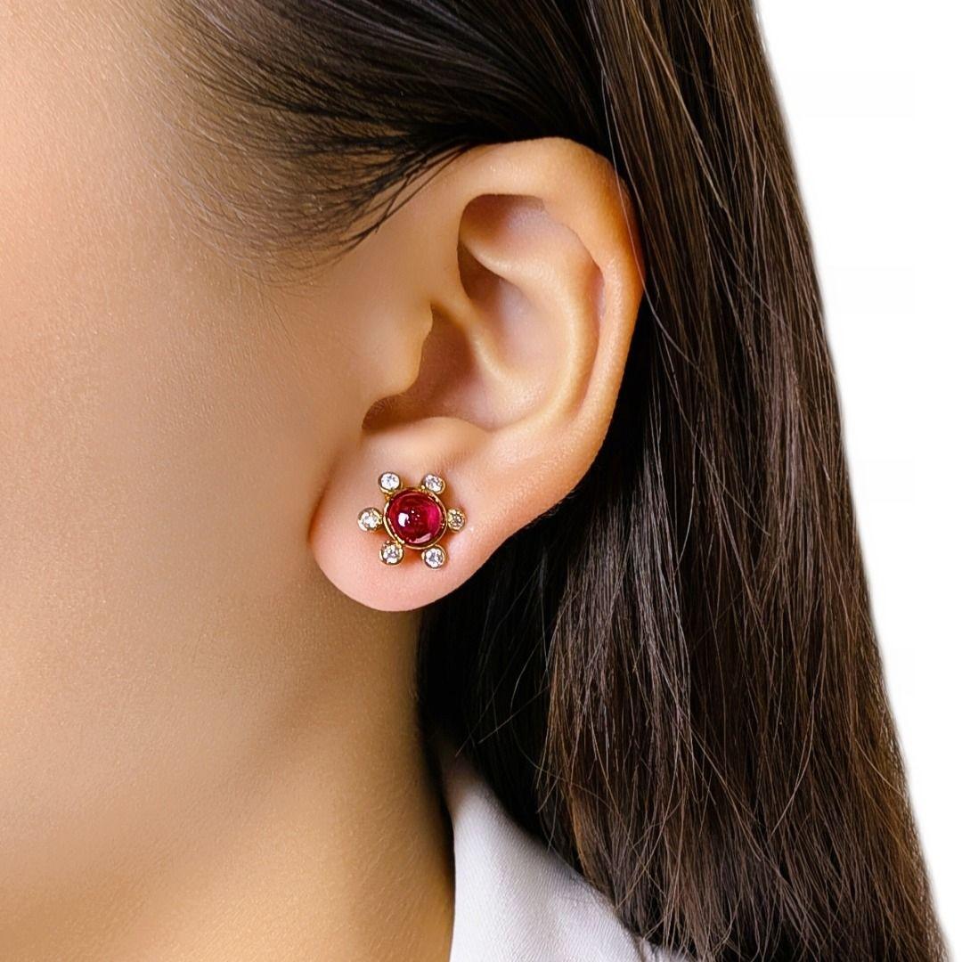 Questi incantevoli orecchini con perno presentano 2 rubini taglio cabochon (1ct in totale) in una ricca tonalità rossa, incorniciati da 12 diamanti tondi taglio brillante (0,30ct), di colore J e purezza SI, disposti in una delicata esplosione