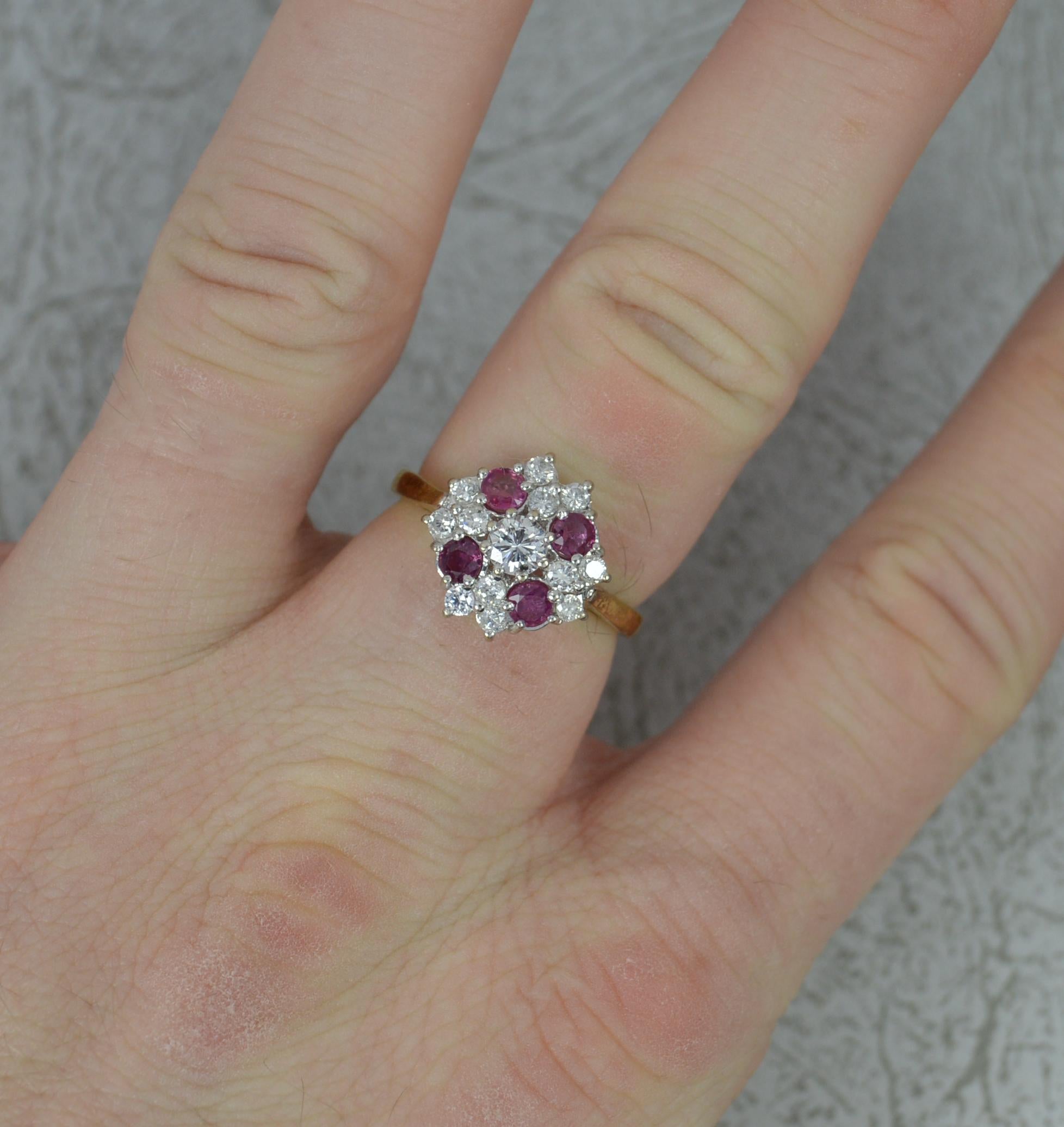 A striking vintage cluster ring.
Solid 18 carat yellow gold shank, white gold head.
Designed with a larger round brilliant cut diamond to centre. Surrounding are twelve small round brilliant cut diamonds and four vibrant pinky red rubies. All
