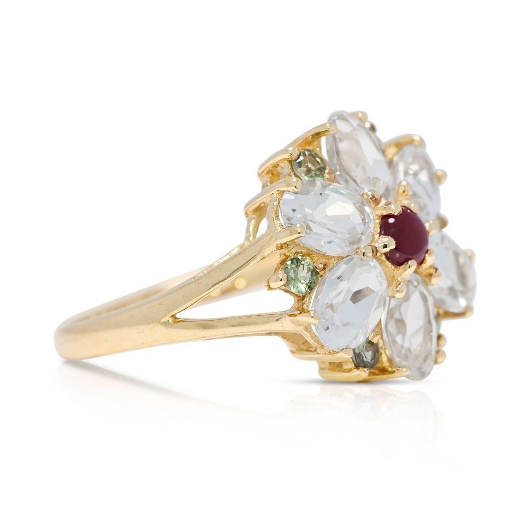 A dazzling fusion of color and elegance, this 9K yellow gold ring features a 0.09ct round brilliant-cut rubellite, radiating a striking red hue at its center. Accentuating its beauty are six oval-cut topaz stones, totaling 1.68 carats, in a luminous