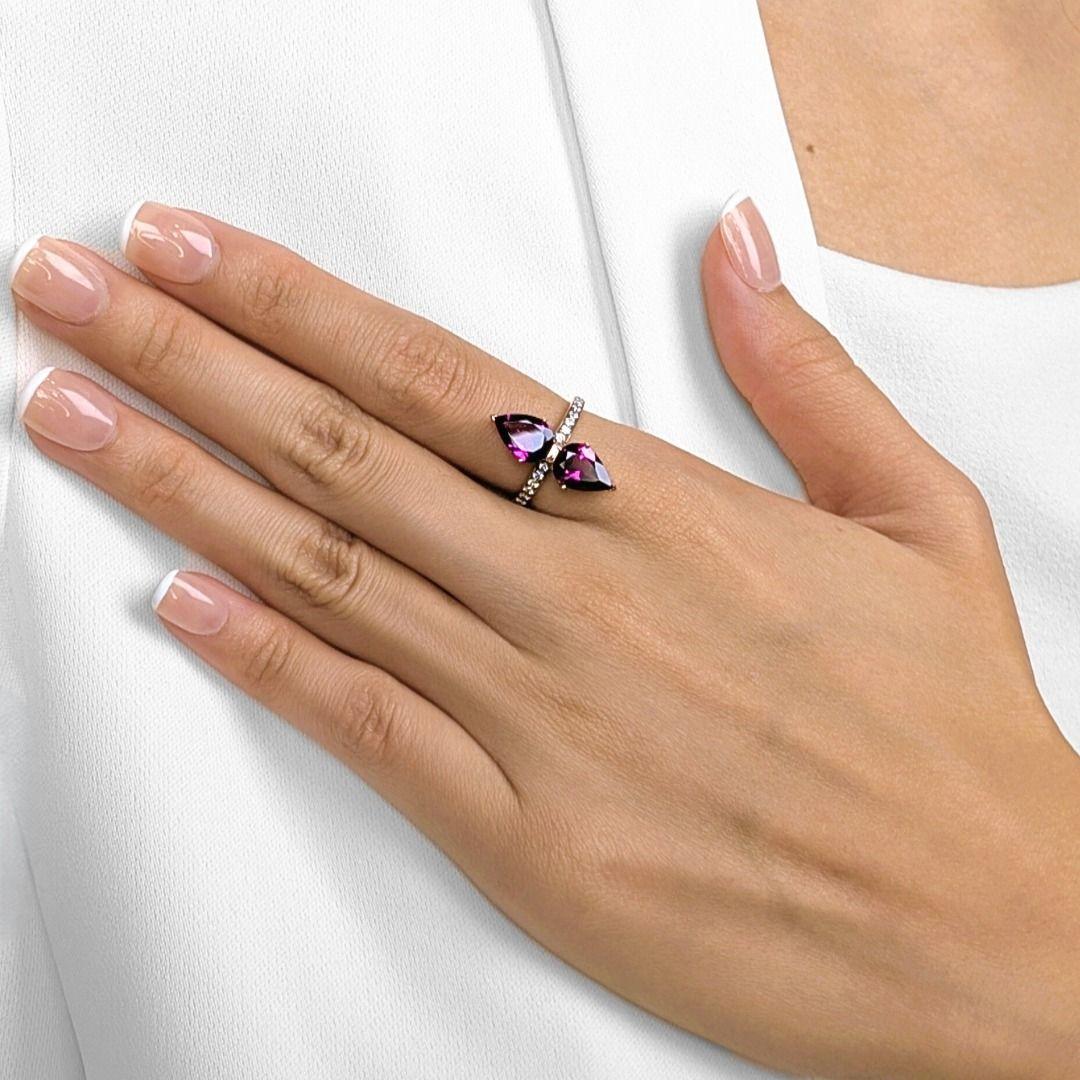 This alluring ring is a celebration of color and elegance, showcasing two pear-shaped purple tourmalines totaling 2.78ct, set in a striking mirrored design. Accenting the vibrant gems, 16 natural round brilliant diamonds (0.32ct total, I–J color, VS