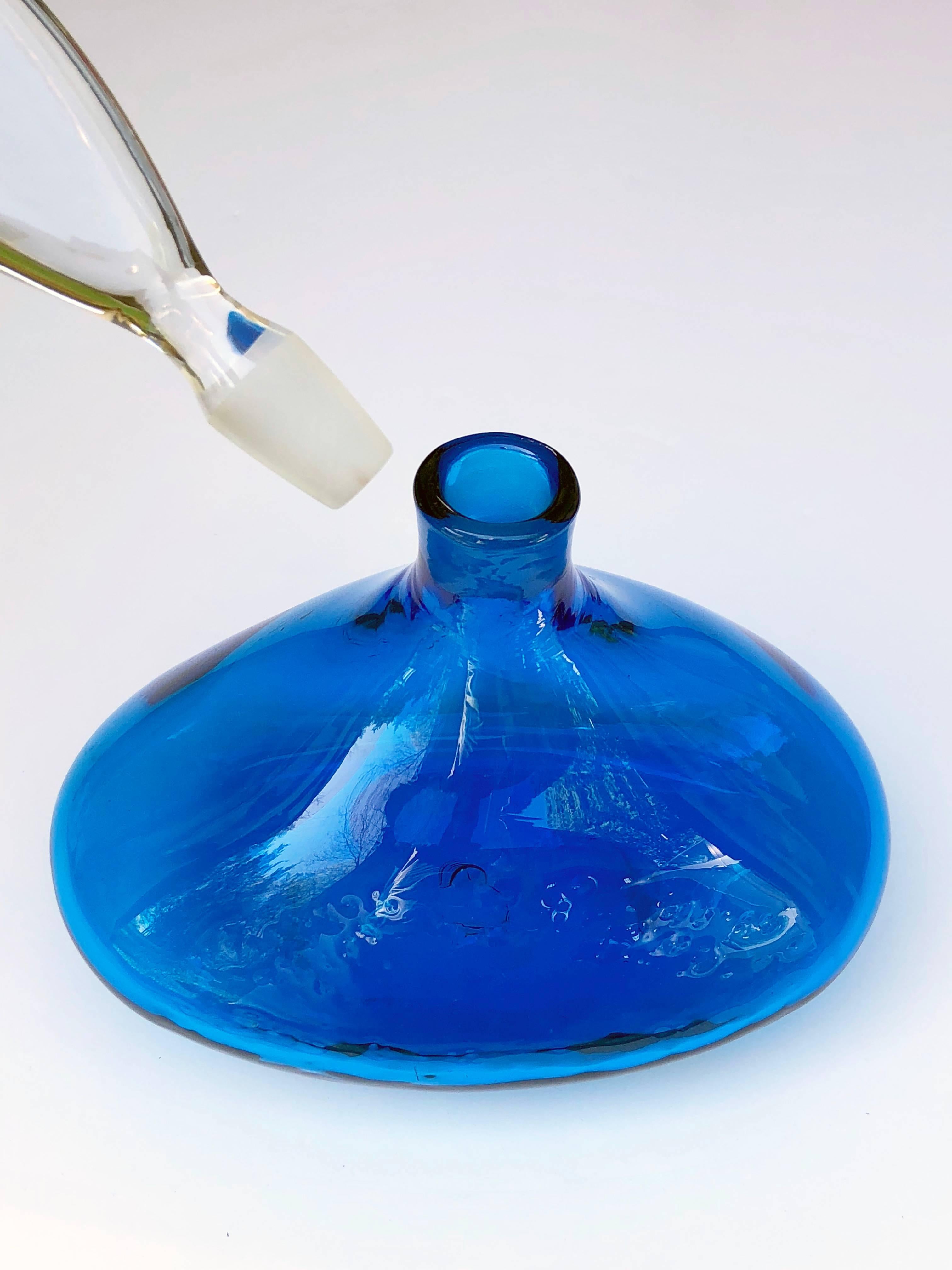 A vibrant American 1960s blue glass ships decanter with over-scaled stopper, by Blenko glassworks, the very cool decanter with large clear glass paddle-form stopper resting on a vibrant blue base.