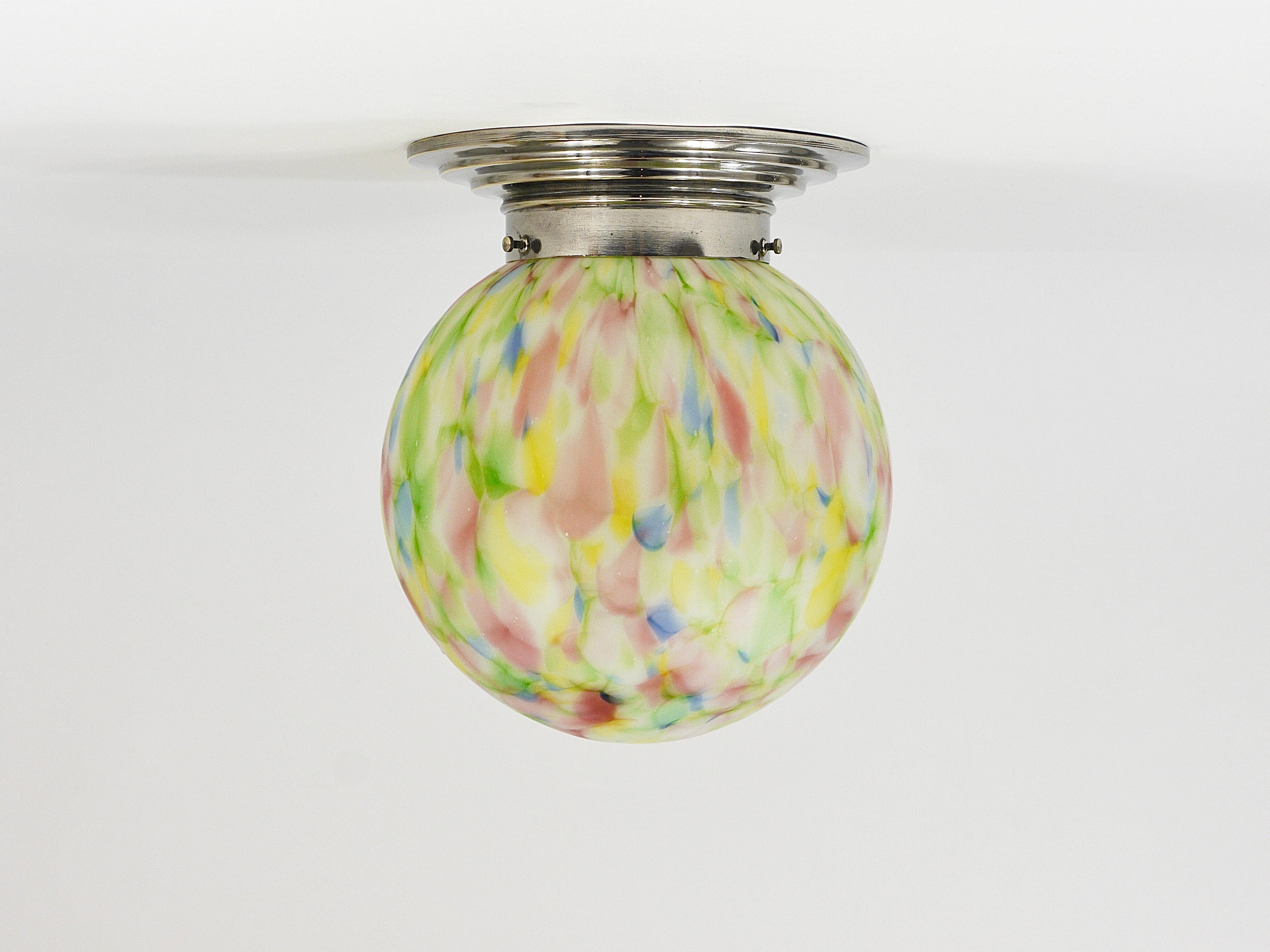 A colorful brightly marbled Art Deco ball ceiling lamp from the 1930s, made in Germany. The light features a stepped round mount made of nickel-plated brass and a beautifully marbled blown spherical lampshade, handcrafted from white, red, yellow,