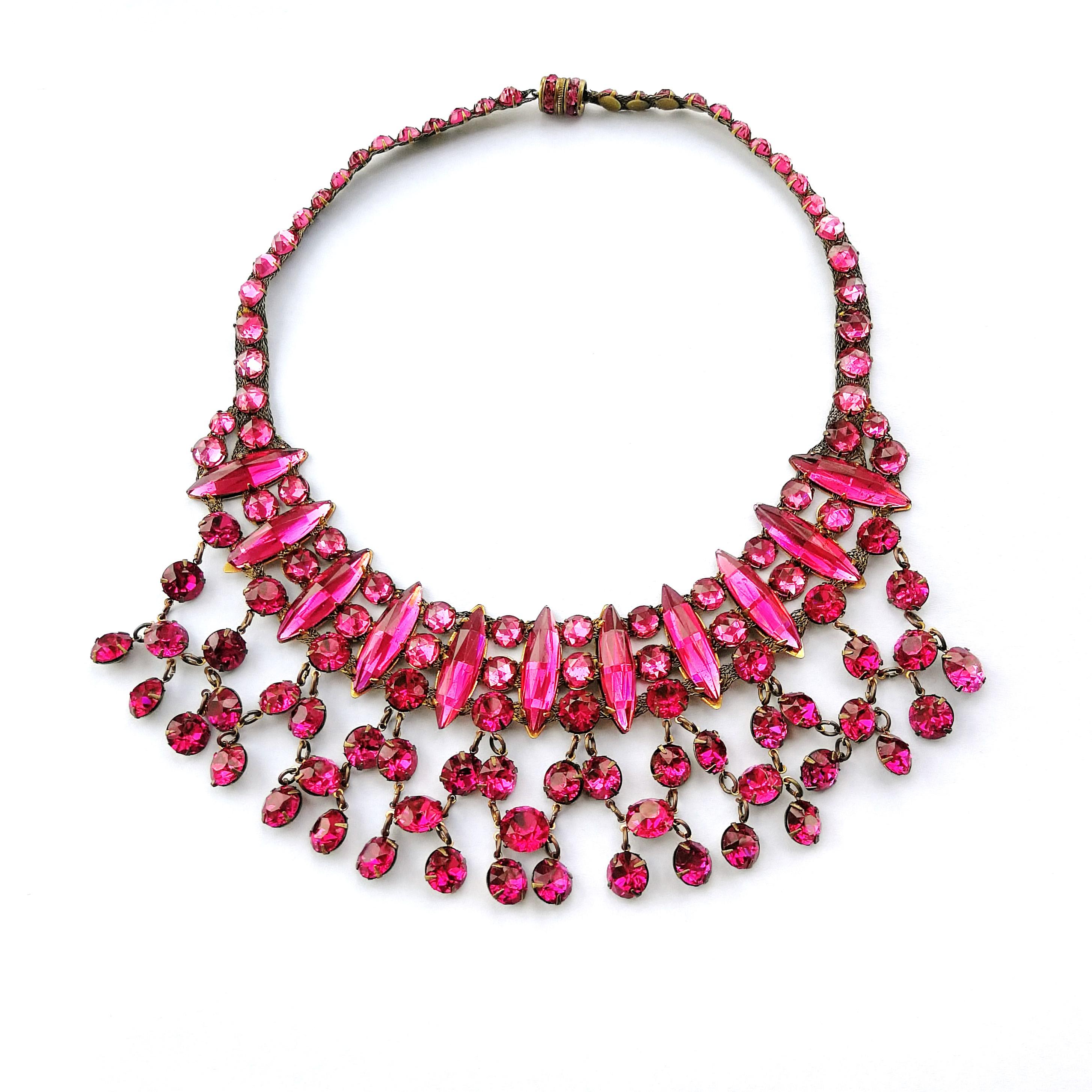 A very rare and ravishing necklace, set in a soft gilt metal, with the most vibrant and extraordinary cerise glass faceted round cabuchons, ovoid cut glass plaques and round cut glass pastes, articulated around the front of the necklace. Set all