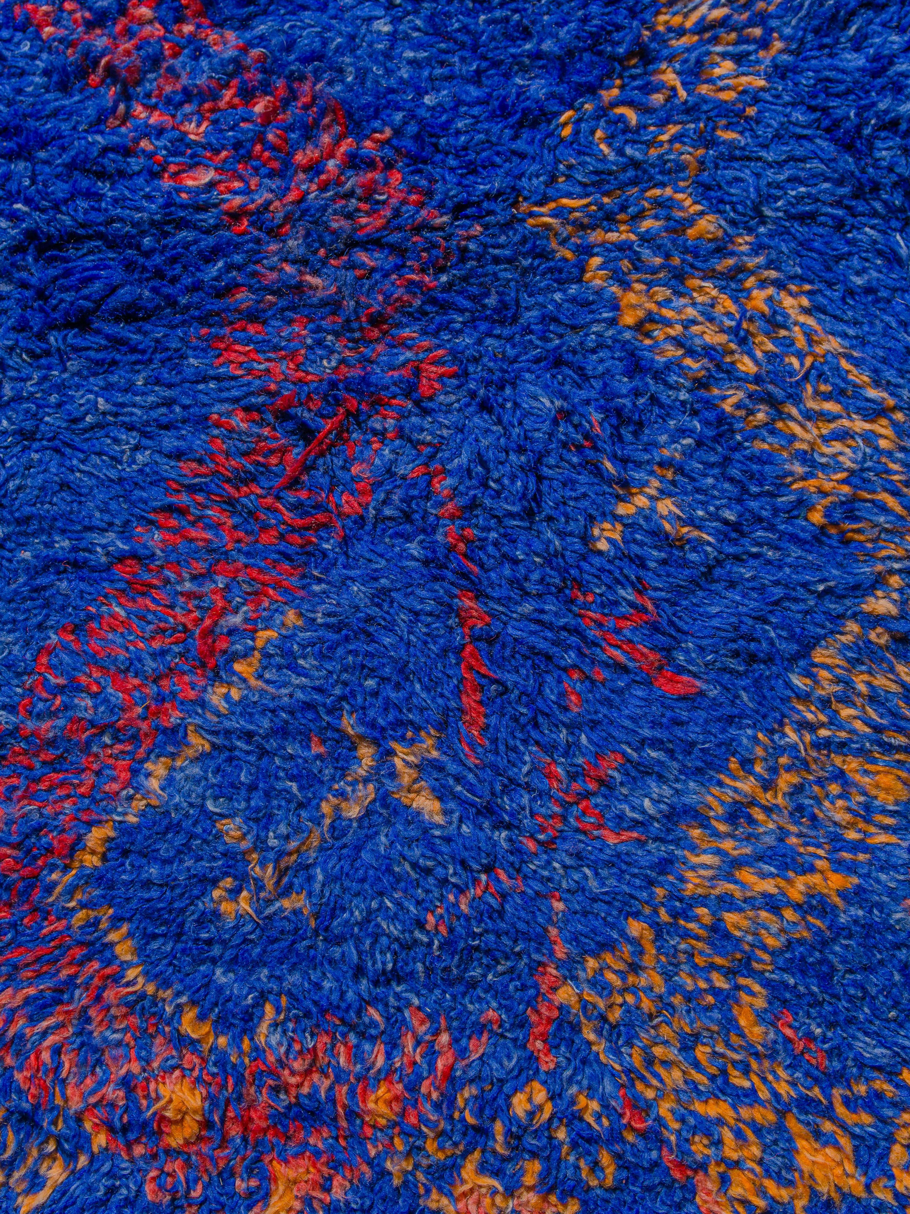 A vibrant cobalt blue Beni M’Guild with striking red and orange zig zag motifs running in parallel, eventually shifting and converging to form loose lozenges. Smaller symbols are scattered at opposing ends, providing a momentary change in rhythm.