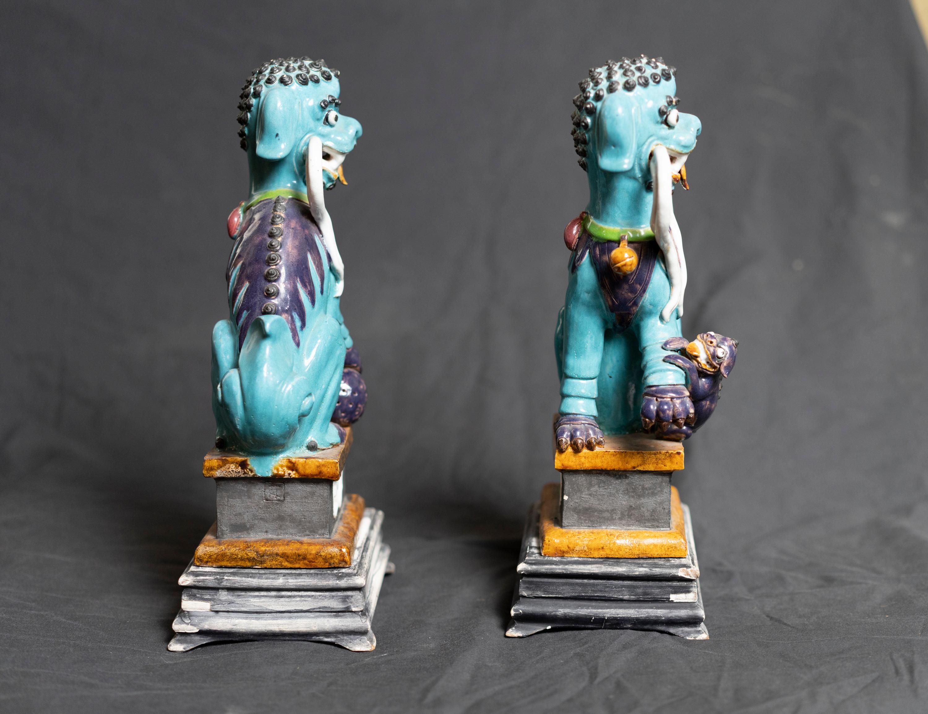 Pair of glazed ceramic foo dog sculptures for birks resting on painted on wooden base
Marked: 