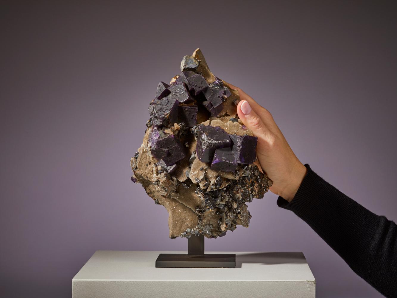 Maravíllate ante la impactante belleza de este vibrante espécimen de fluorita procedente de EE.UU., adornado con impresionantes formaciones cúbicas. El profundo tono púrpura de los cristales de fluorita contrasta maravillosamente con el brillo