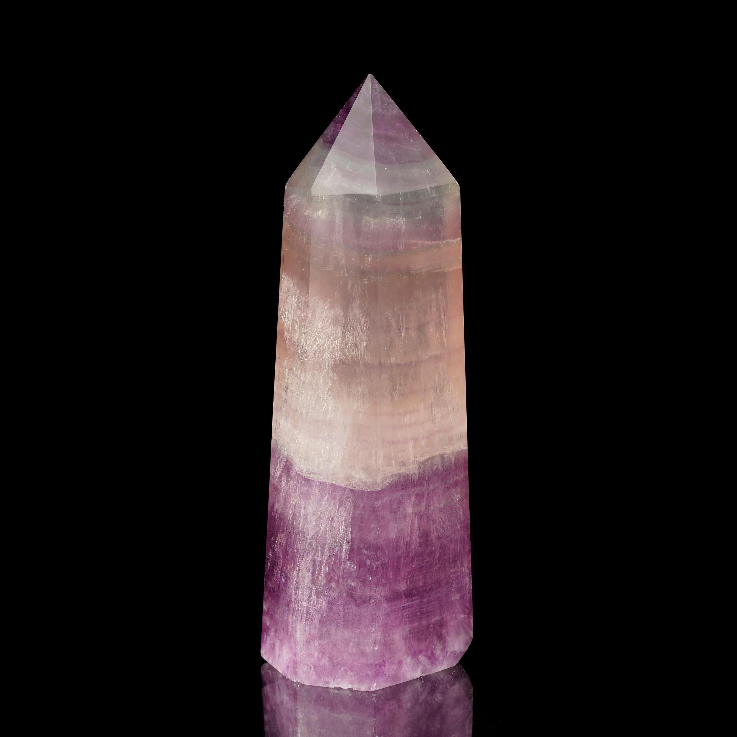This stunning Fluorite obelisk comes from China, a region renowned for its vivid and highly prized Fluorite specimens. With its captivating bands of purple, green, and blue, Fluorite is known for its ability to enhance mental clarity and focus. The