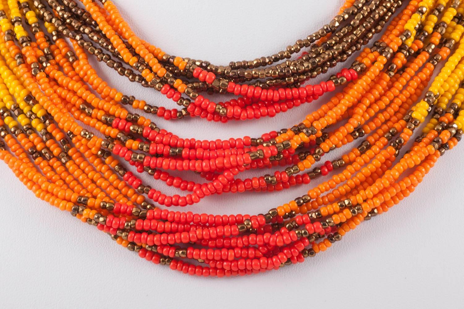 A highly vibrant and wonderfully cheerful multi strand beaded necklace by Miriam Haskell, bursting with yellow, ochre, orange, red  coloured small beads, shot through with bronze coloured beads, with a nod to American Indian design. It has a fixed