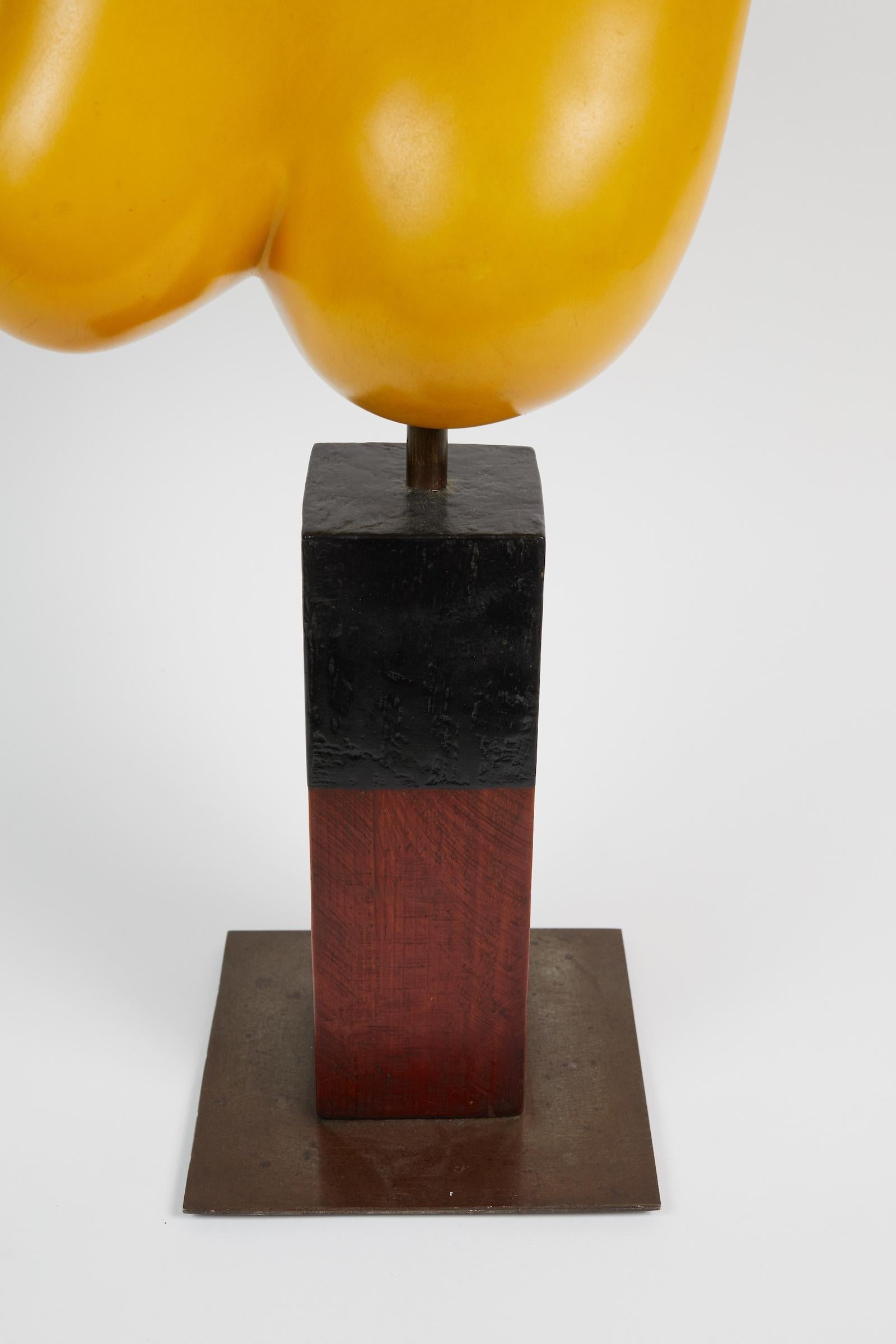 Yellow painted resin sculpture by Henry Wanton Jones resting on a wood and steel base.
Signed under the base 