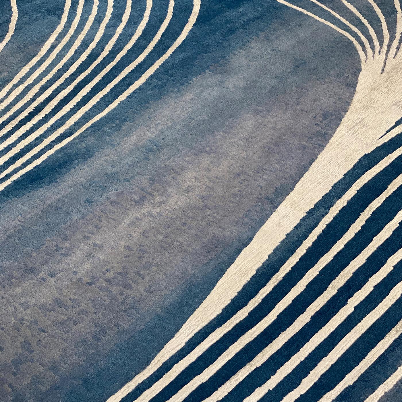 This evocative rug is a captivating addition to contemporary decor, where it will capture the eye with its mesmerizing motif of sinuous threads bursting into the blue backdrop as vibrations into space. Hand-knotted by Nepalese artisans using 50%