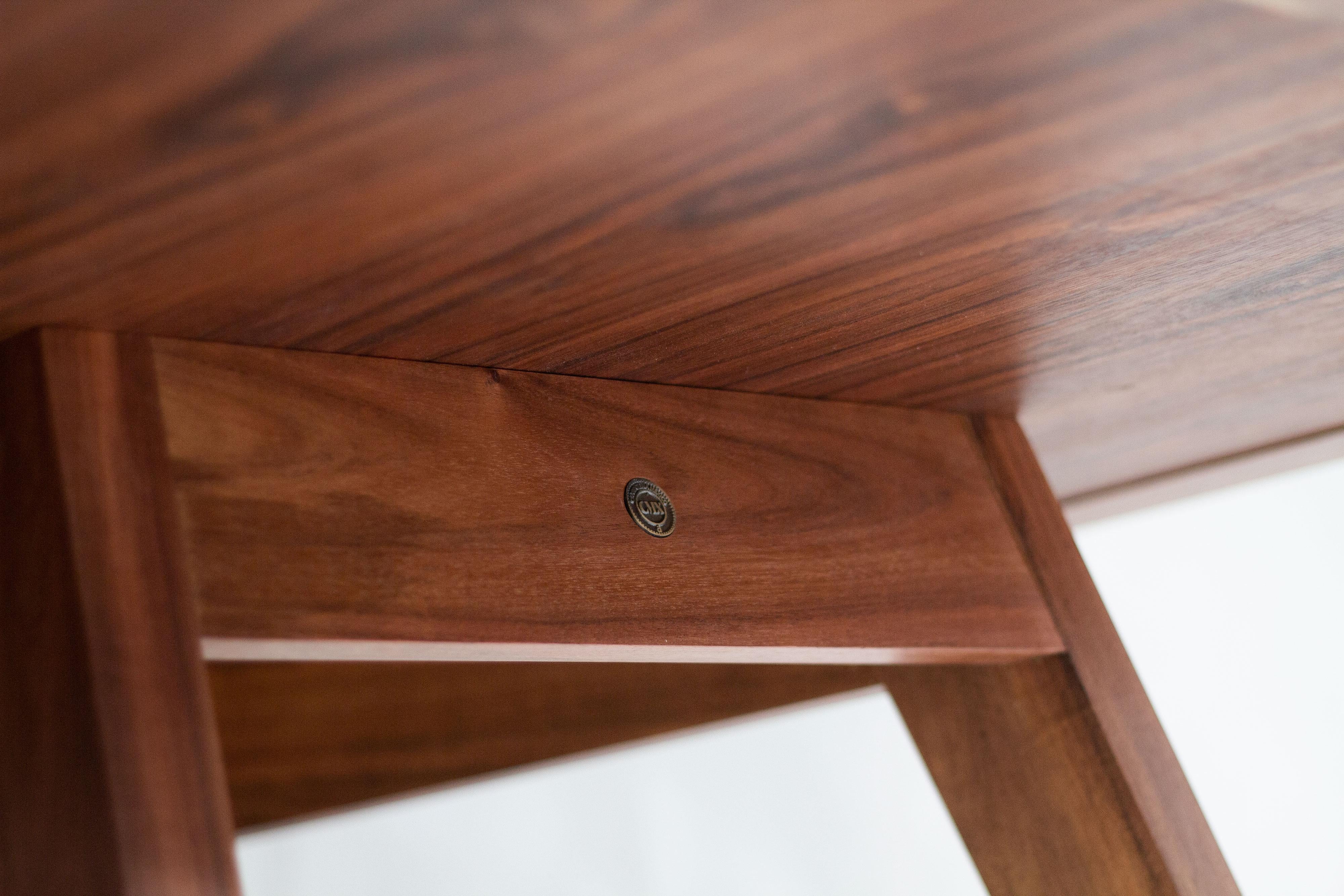This rectangular dining table features a striking granite top, offering both durability and a sleek, modern aesthetic. The solid walnut base adds warmth and contrast, with its rich wood tones and sturdy construction providing excellent support.