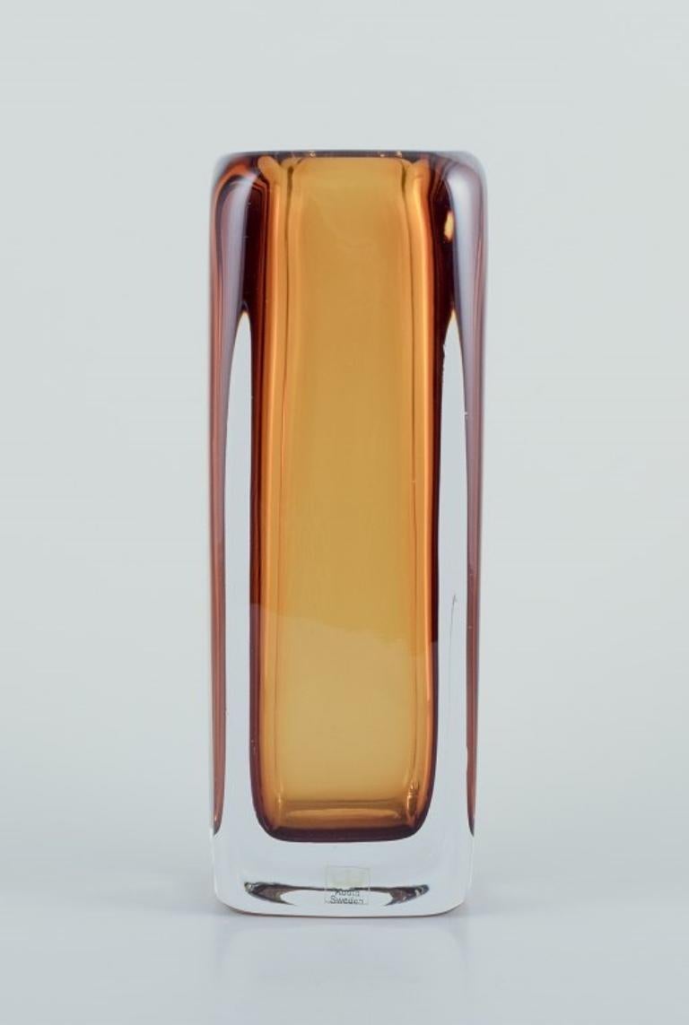 Vicke Lindstrand per Kosta Boda, Svezia. 
Vaso in vetro artistico in vetro giallo e trasparente. Soffiato a bocca.
Forma quadrata.
Numero di modello 1898.
Dagli anni '70.
Etichetta.
Firmato.
Condizioni perfette.
Dimensioni: H. 22,0 cm x L. 8,0