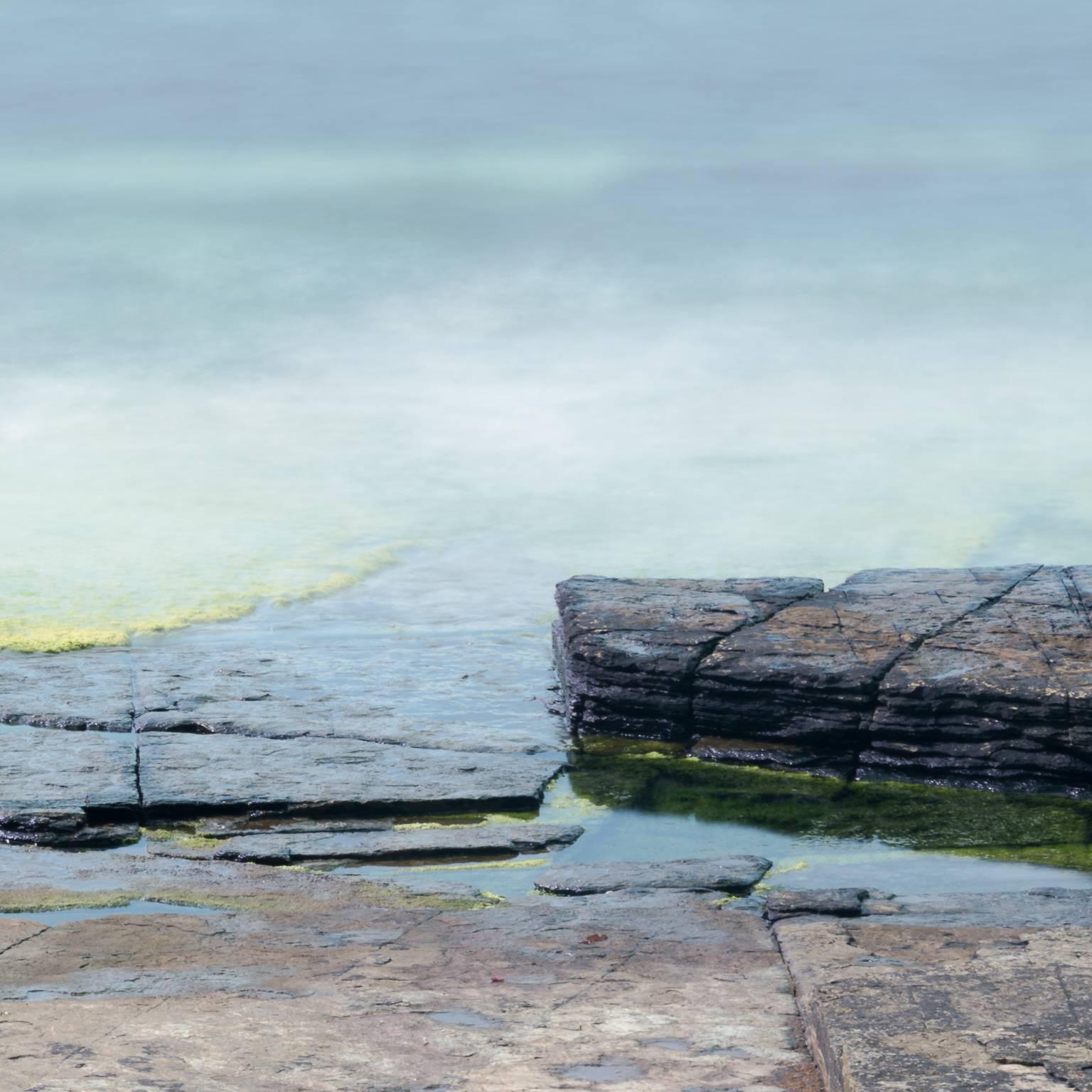 Vicki McKenna's 'Colors of the Sea at Rousay' is a digital file, 7360x4912, of an intimate landscape photograph of the meeting of rock and ocean combining the  subtle browns and greys on the rock with the vibrant blues and greens of the ocean. A