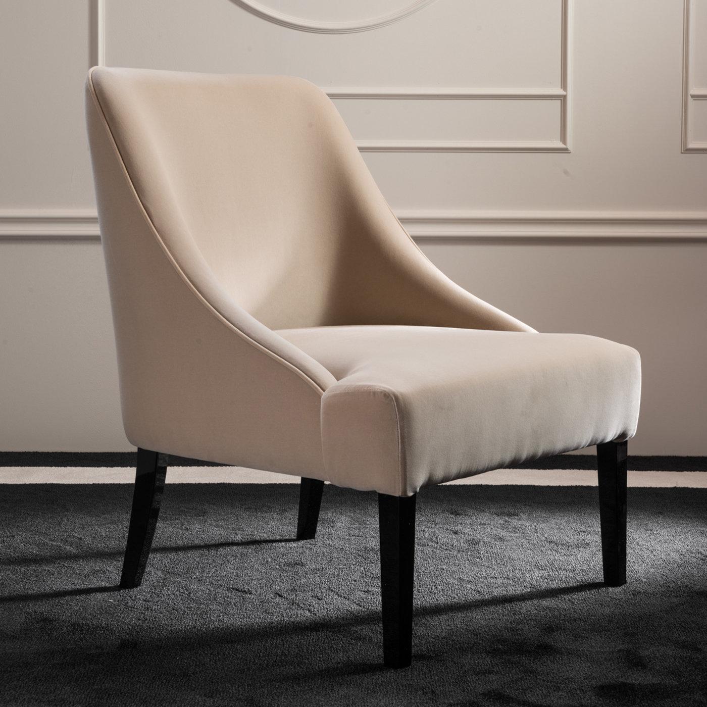 Distinctive for its harmonious and minimalist design, this delicate armchair will as an understated touch of glamour to any modern living room or bedroom. The sturdy wooden frame peeks out in the glossy, black-lacquered legs that support the plush