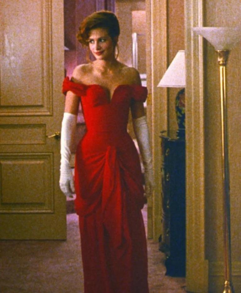 Questo è l'abito originale disegnato da Vicky Tiel, un pezzo iconico poi ricreato per Julia Roberts in Pretty Woman. Realizzato con la sua caratteristica rete elasticizzata increspata e in colore rosso merlot, l'abito presenta una scollatura a cuore