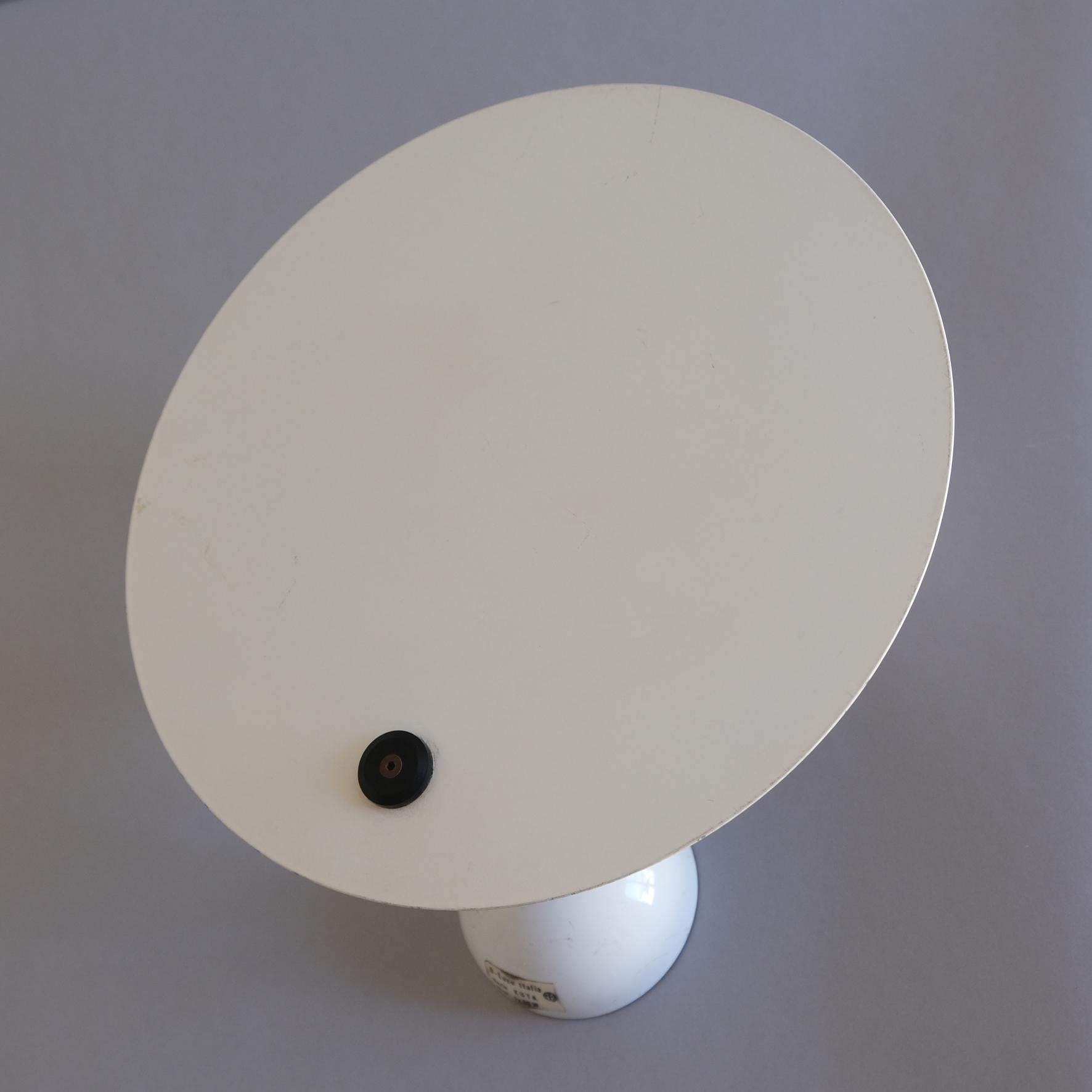 A white and black metal wall applique, the white disk shape reflector supported by a cylindrical branch fixed to a half-spherical wall-mount.
Produced par O’luce, Italy.
Circa 1979.

Literature
Giuliana Gramigna, Repertorio 1950-1980,